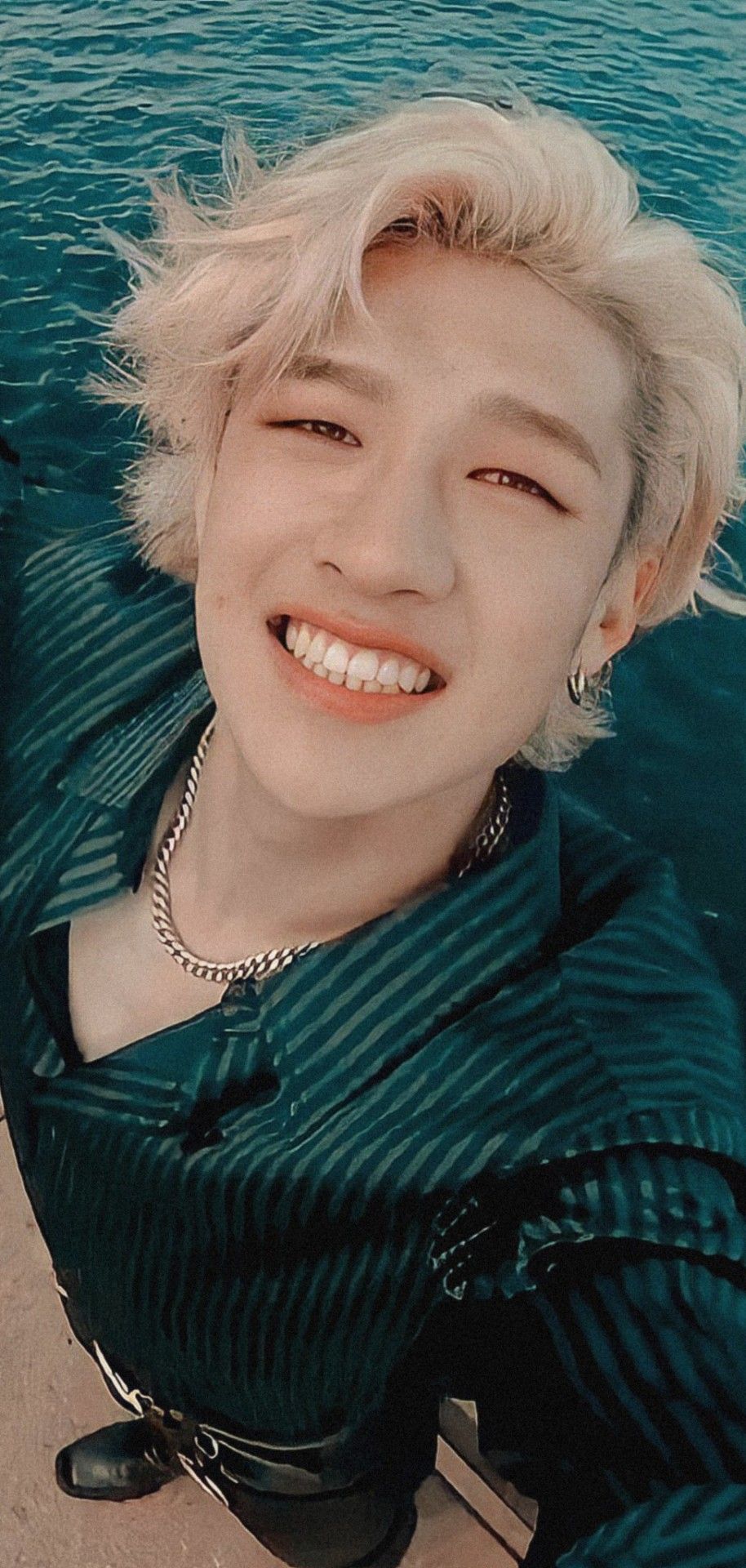 A man smiling and standing by the water - Bang Chan