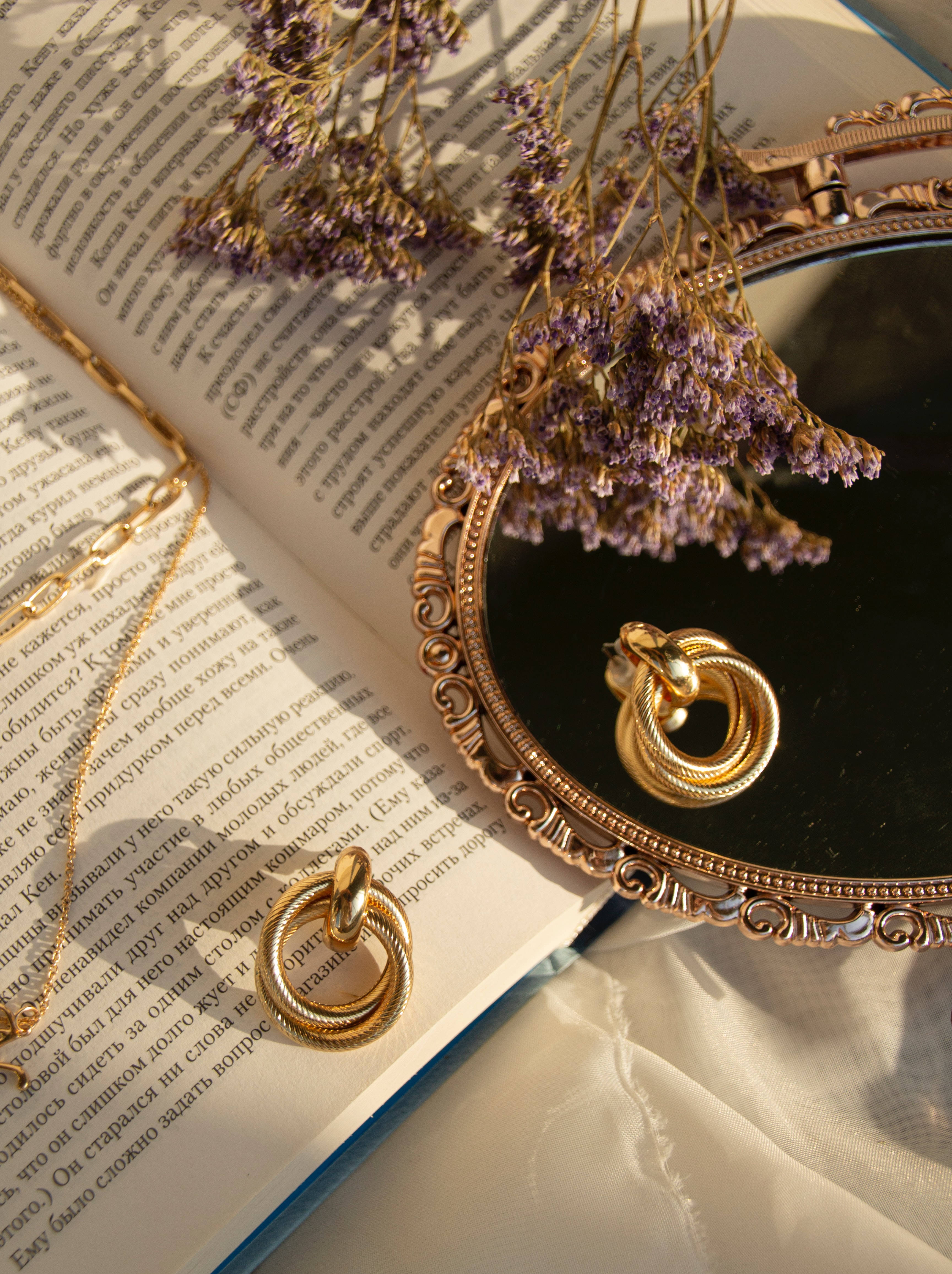 A pair of earrings and necklace on top an open book - Bling, gold
