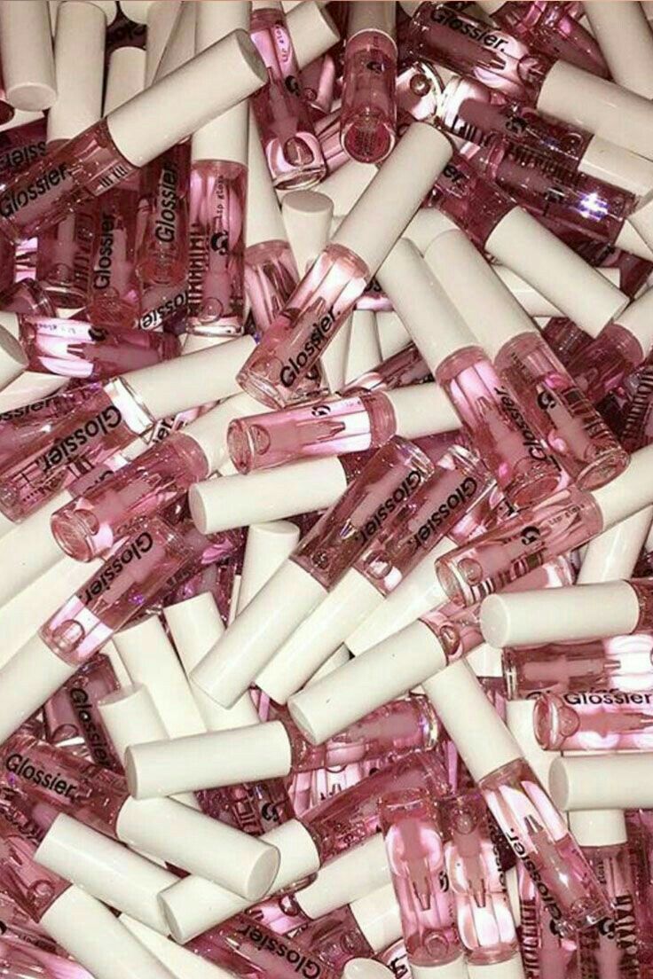 A pile of pink and white Glossier nail polish bottles - Glossy