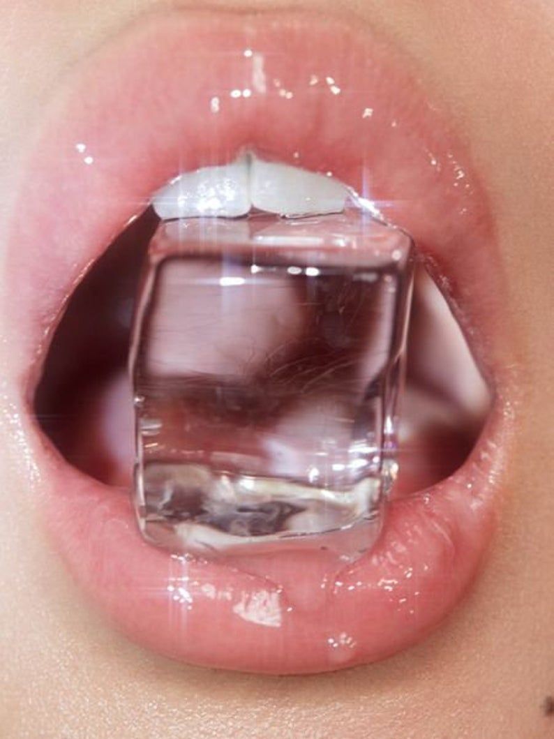 A woman's mouth with a cube of ice in it. - Glossy