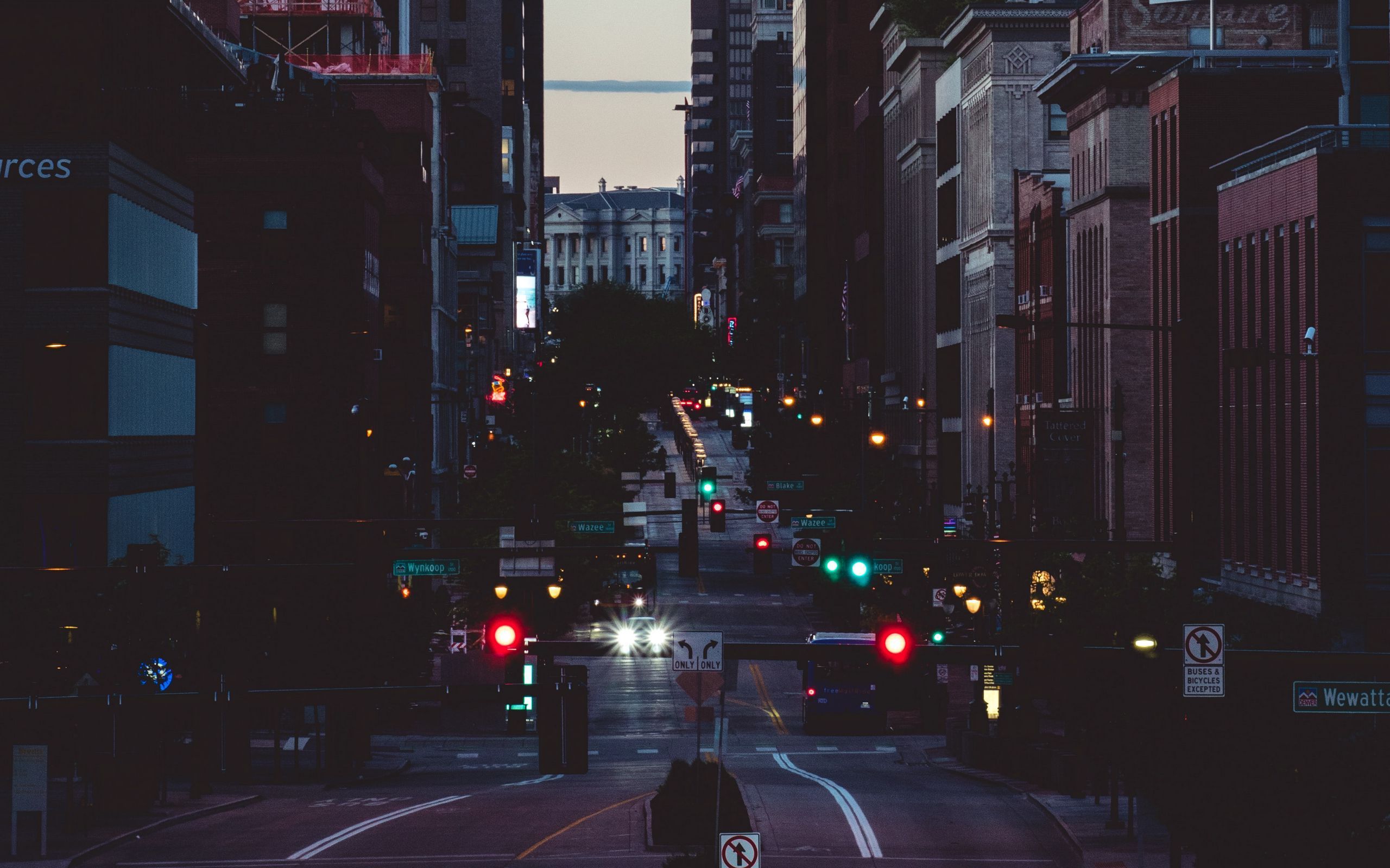 A street in the city at night with traffic lights and street signs. - 2560x1600