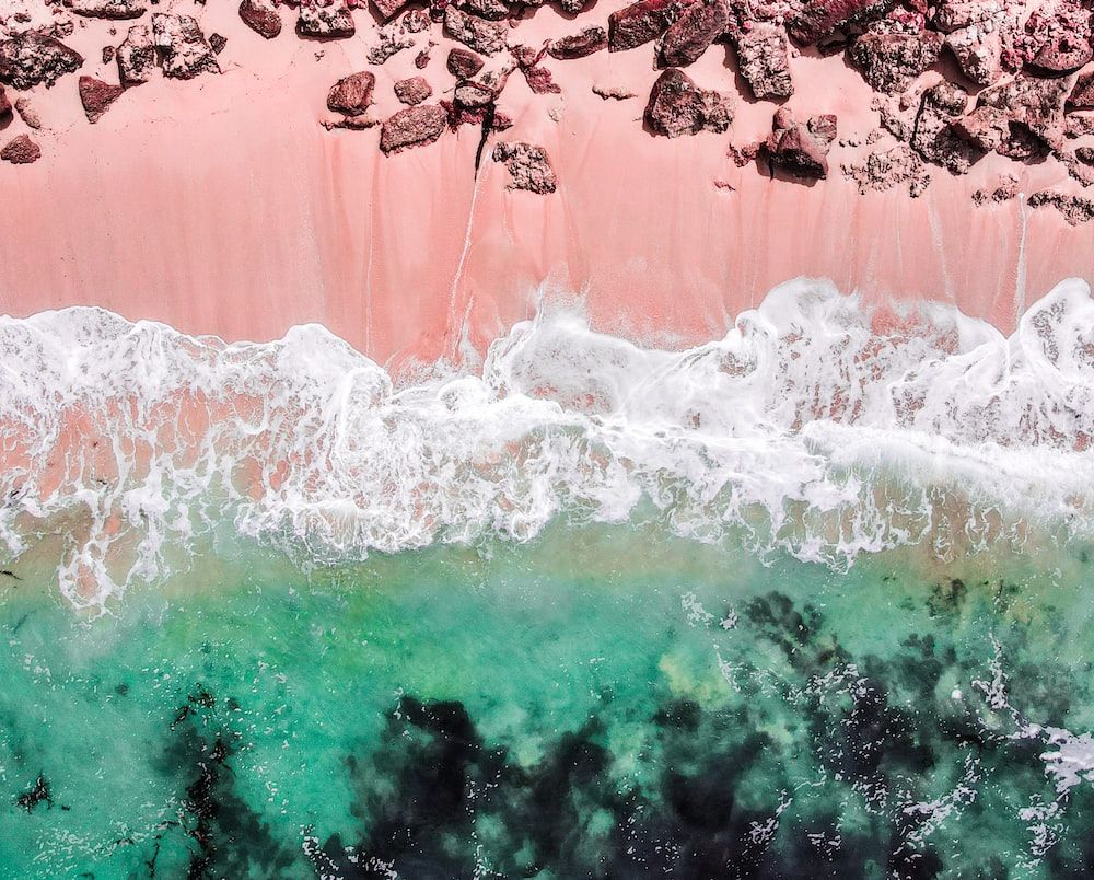 An aerial view of a pink beach with waves - Beach