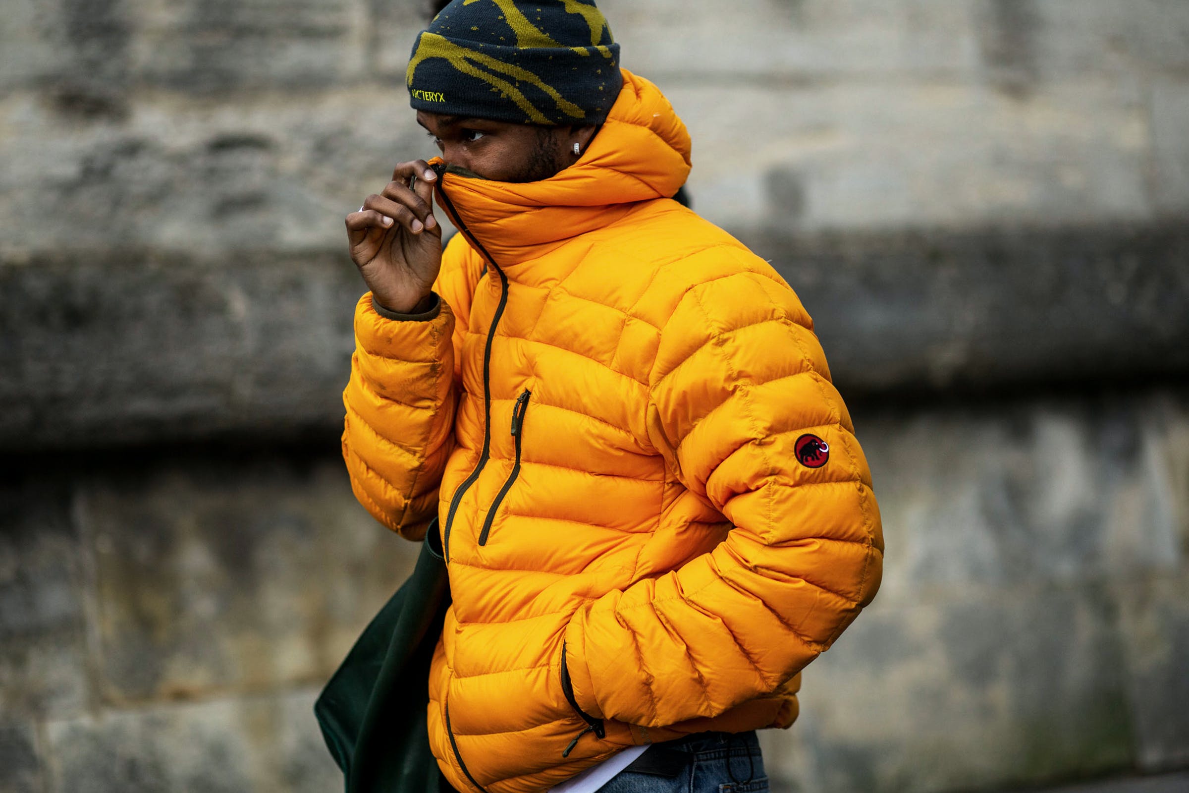 A man wears a yellow puffer jacket and a green and yellow beanie - Gorpcore
