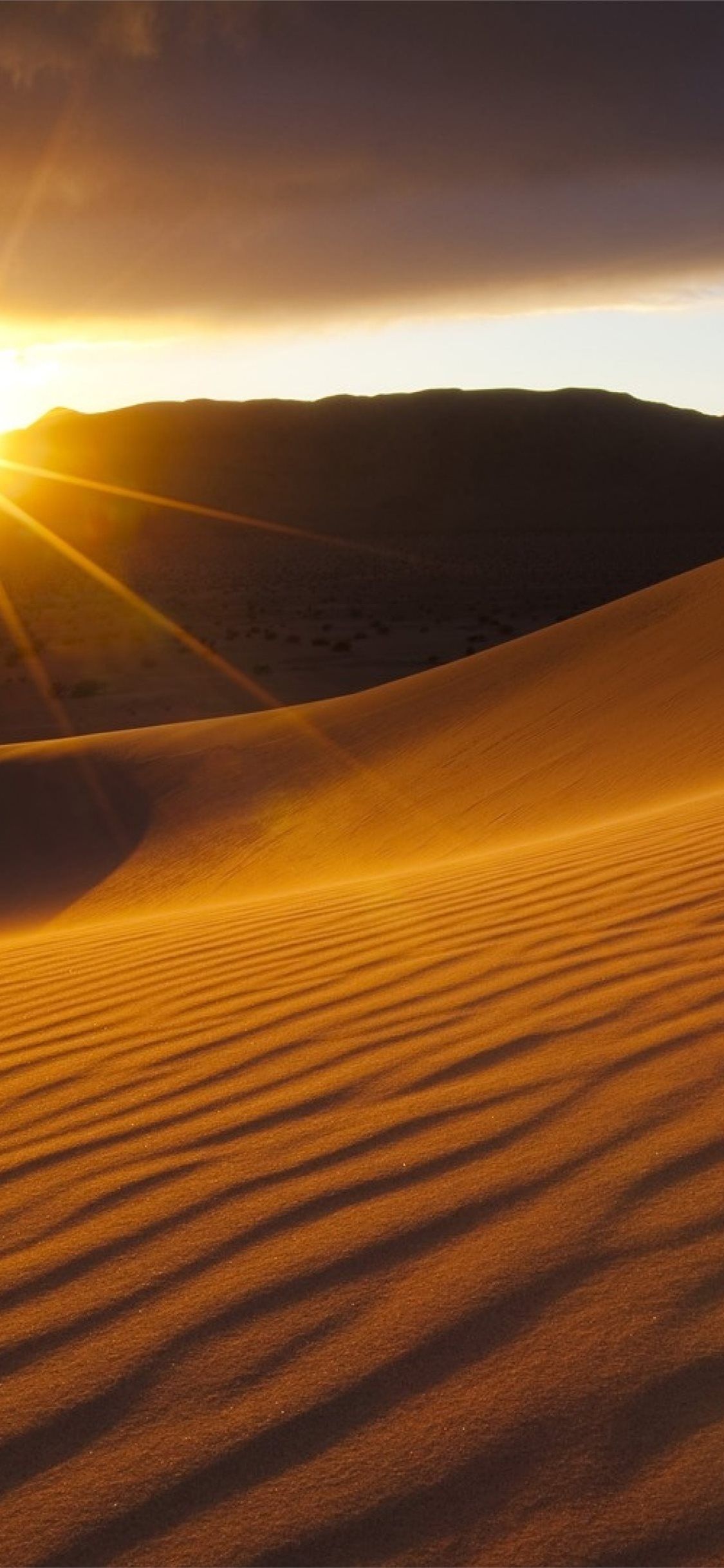 A sunset in the desert with sand dunes - Desert
