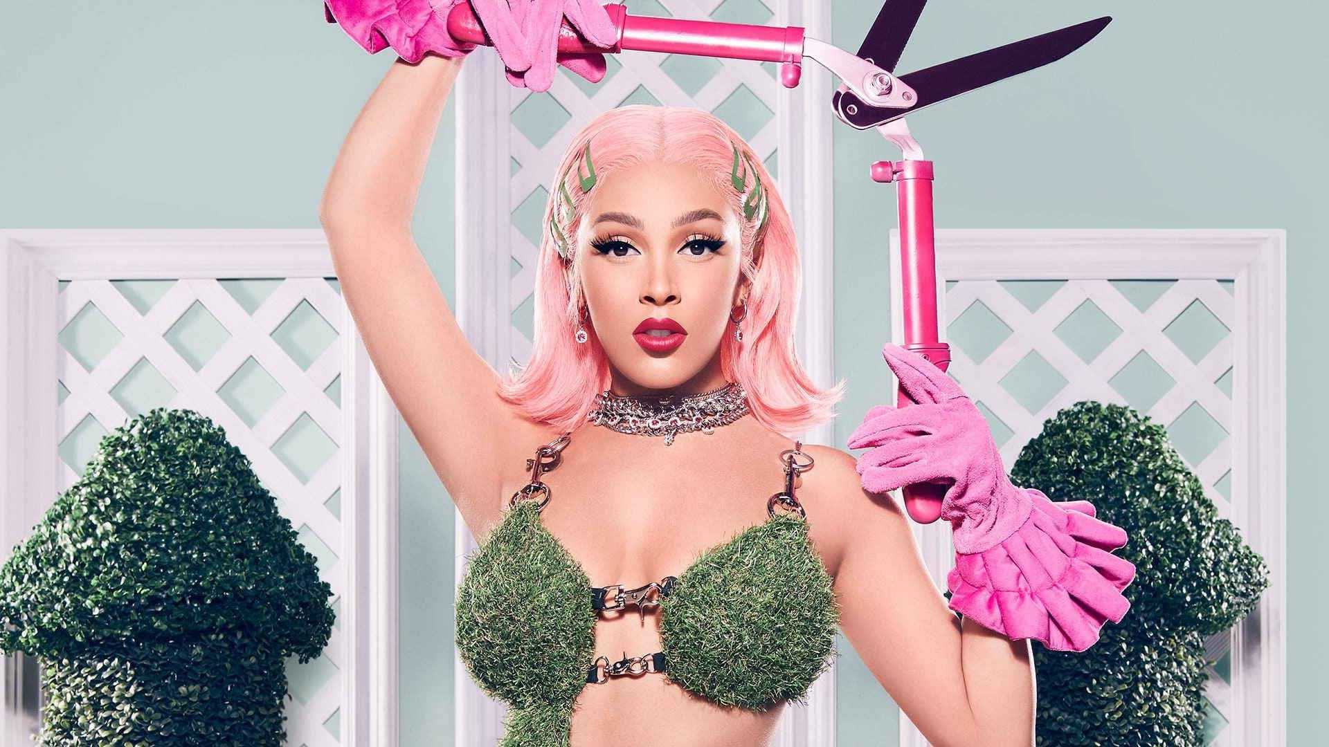 Cardi B in a grass bra and pink gloves holding pink pruning shears - Doja Cat