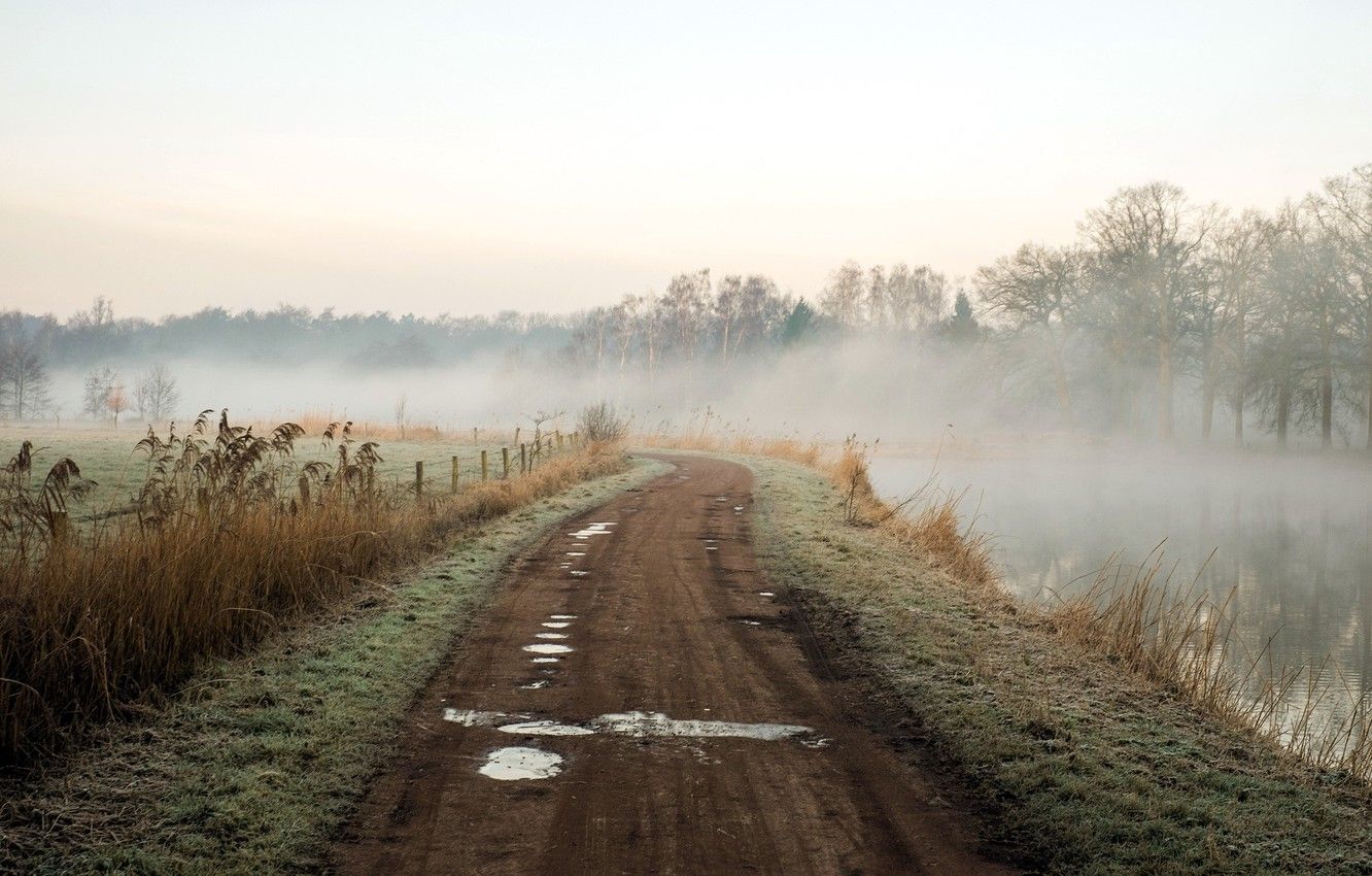 A dirt road that is next to water - Fog