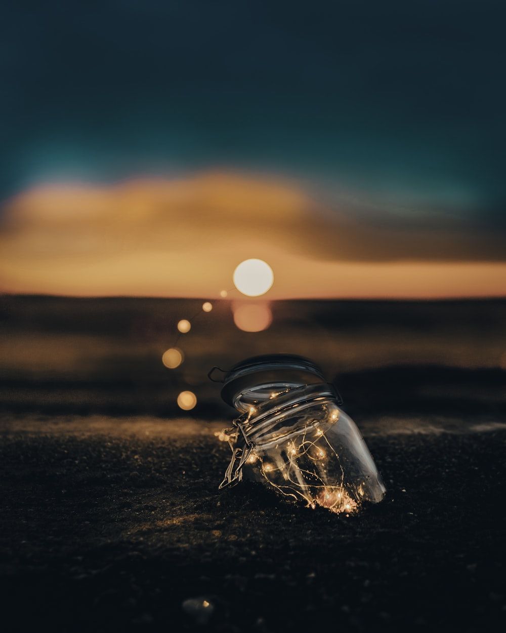 A string of lights in a jar on the beach - Magic