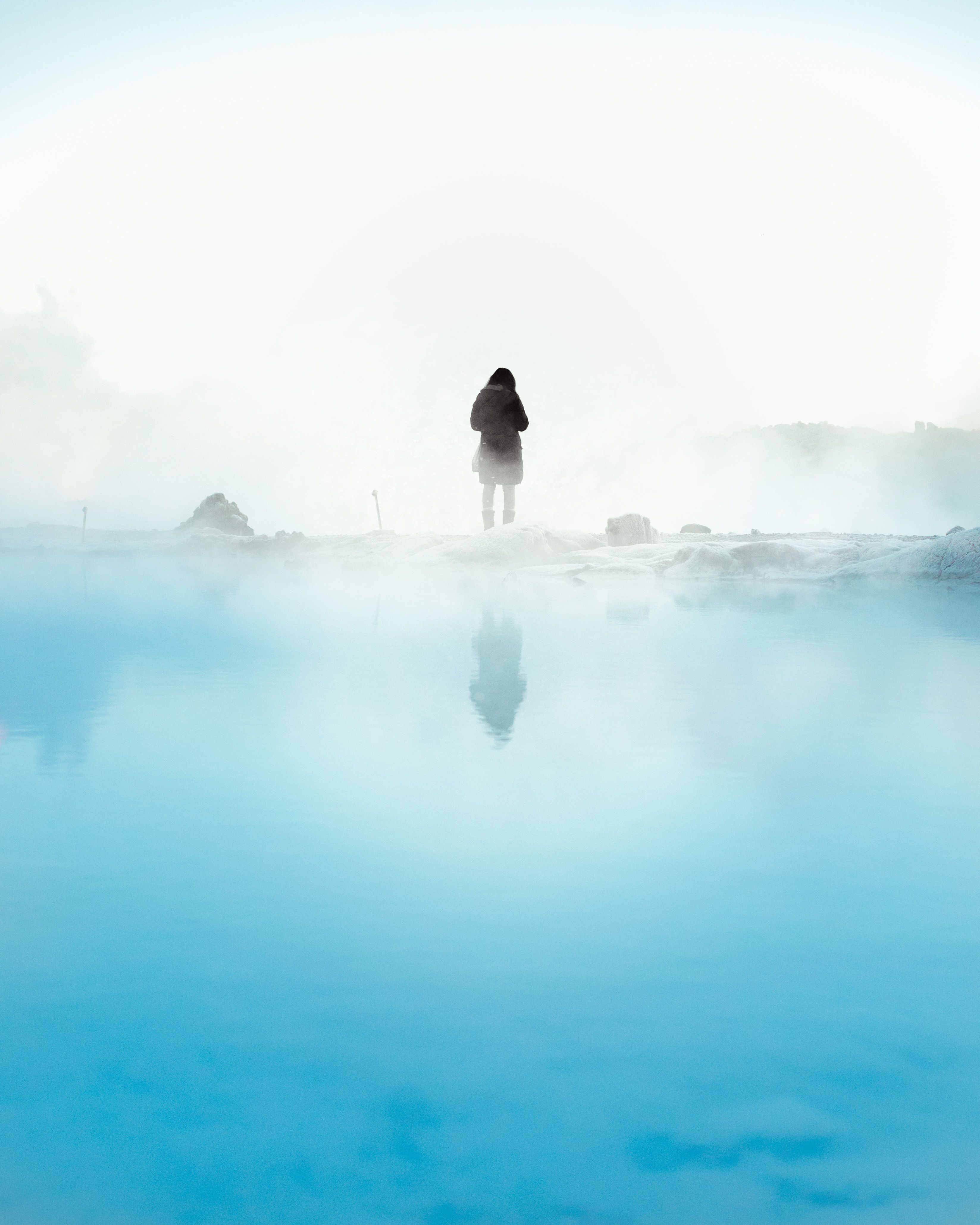 A person standing on the edge of water - Fog