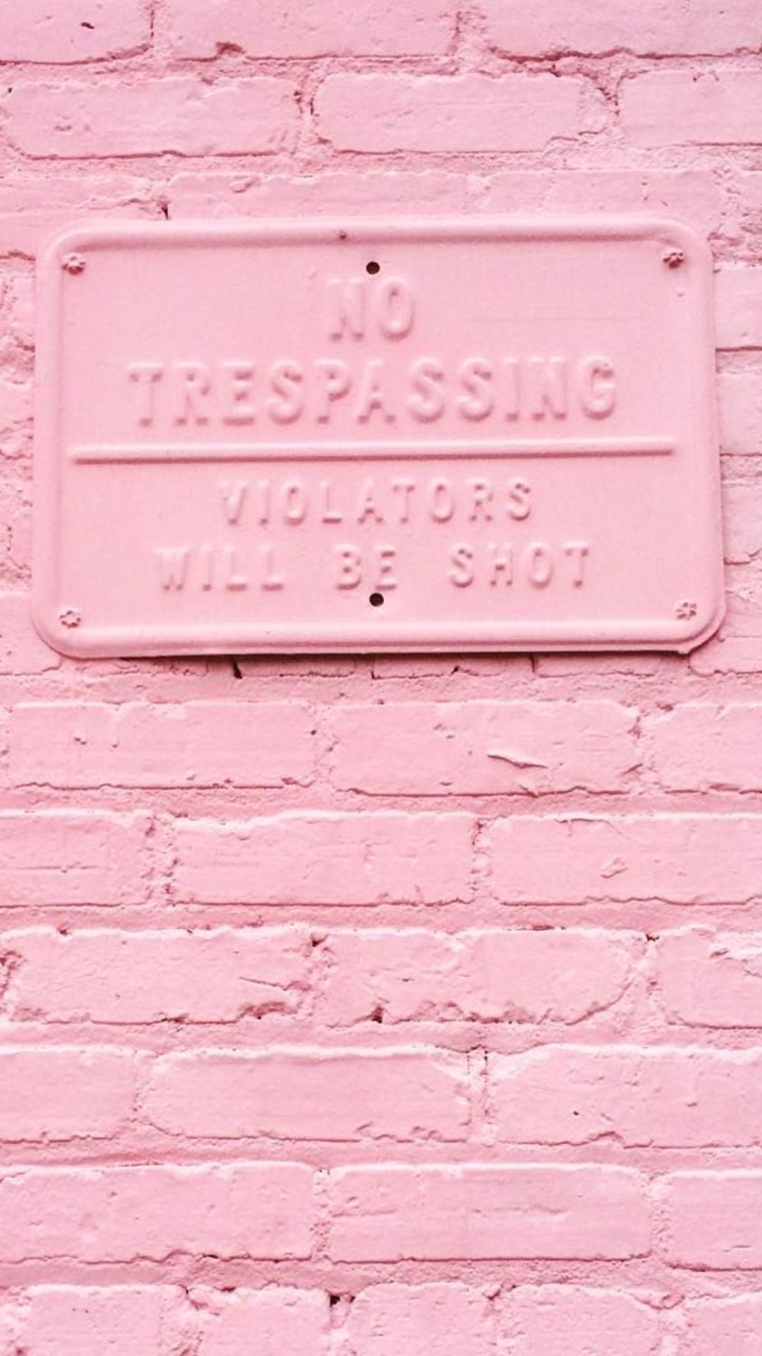 A pink no trespassing sign on a pink brick wall. - Pink phone