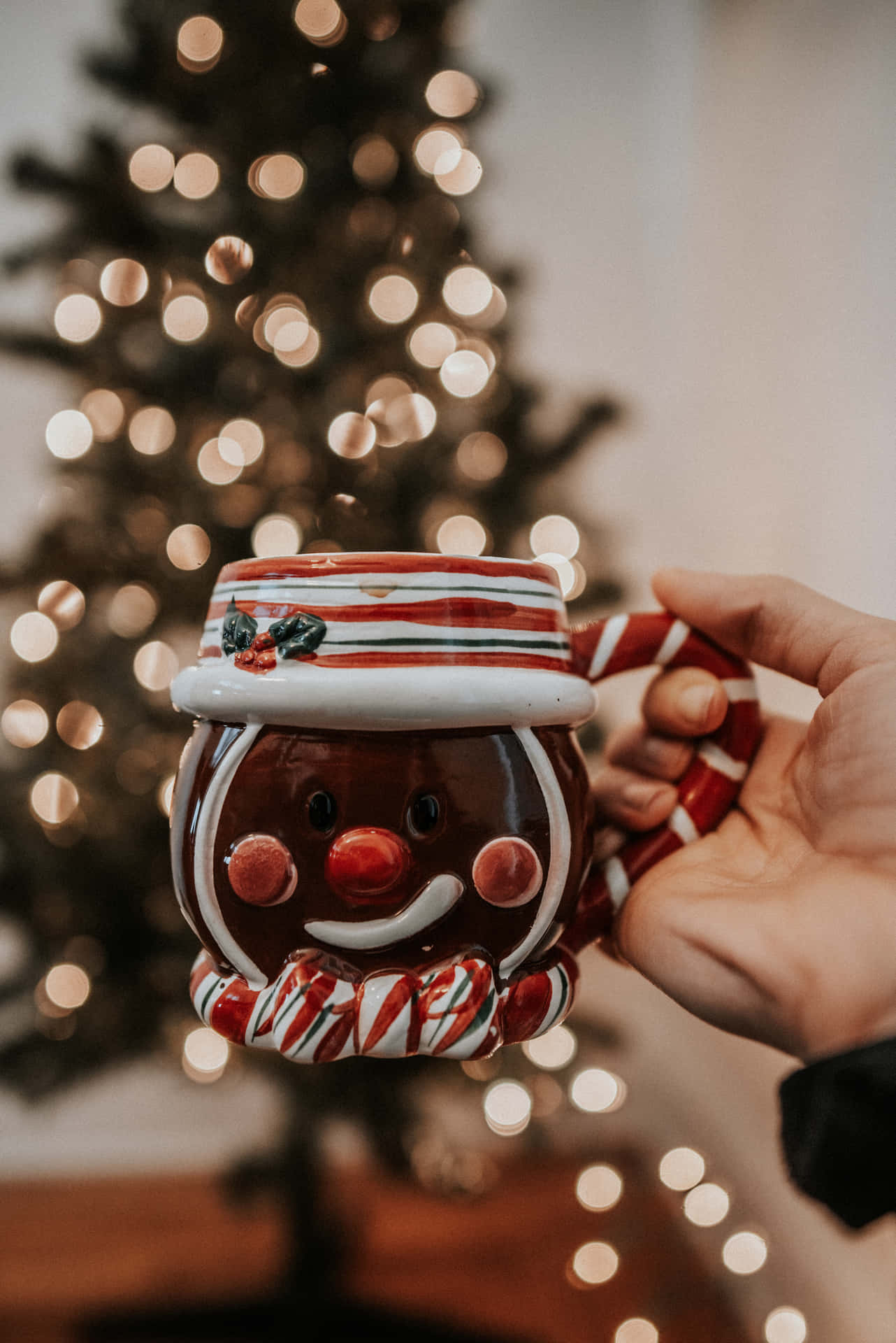 A person holding a Christmas mug in front of a Christmas tree. - Cute Christmas