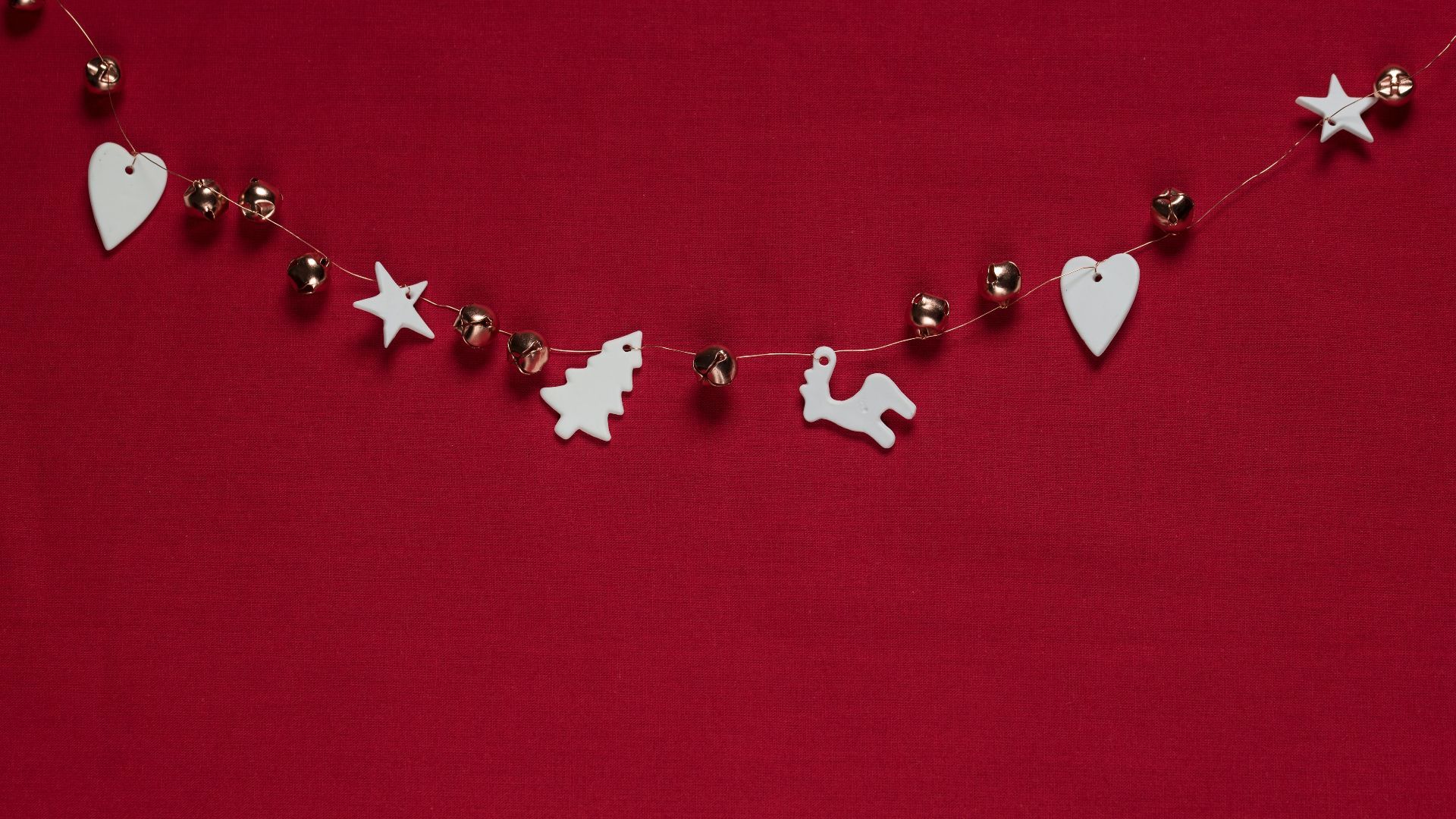 A string of Christmas decorations including stars, trees and deer on a red background - Cute Christmas