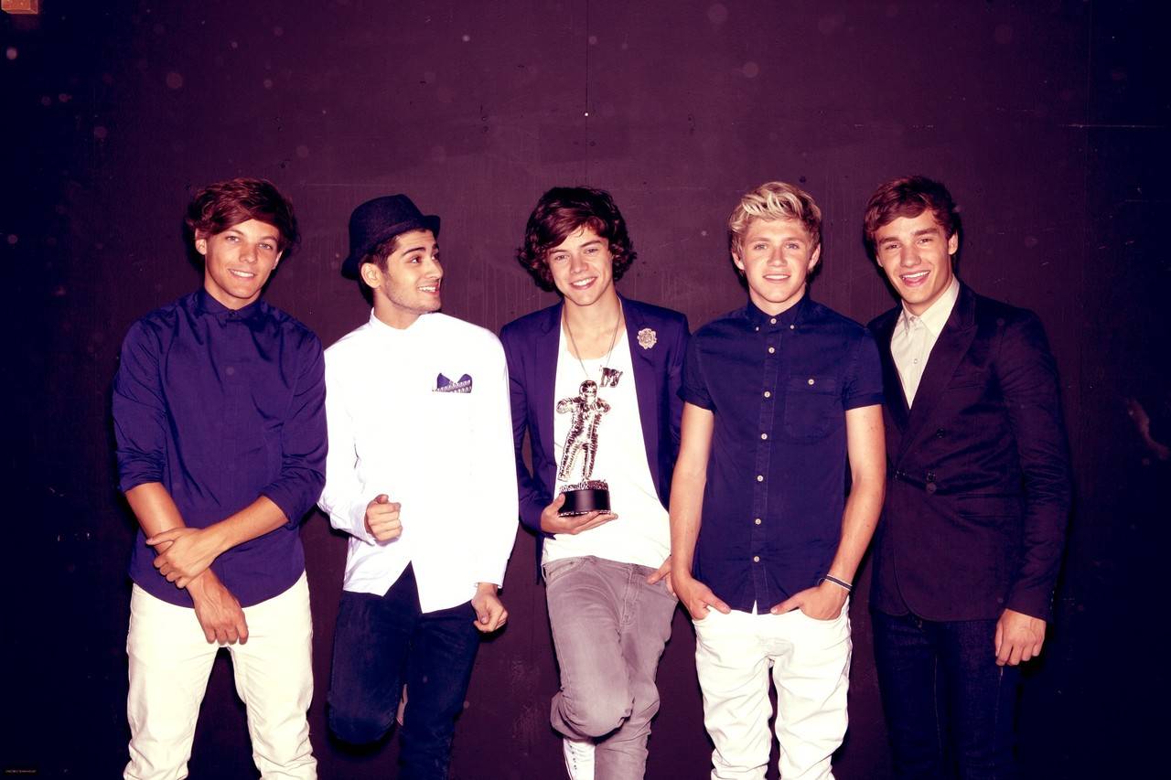 One Direction members standing next to each other holding an award. - One Direction