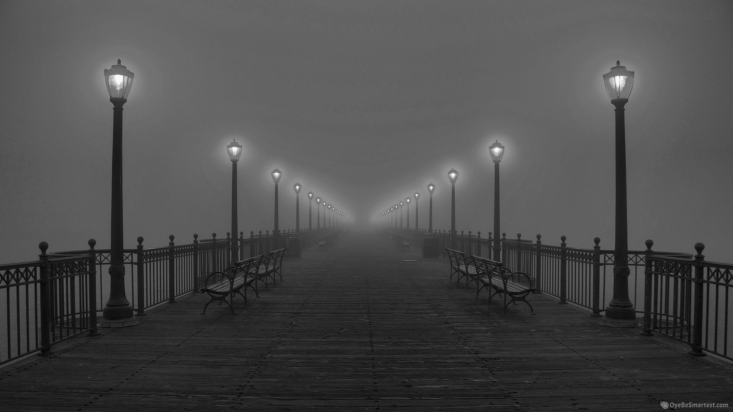 A black and white photo of benches on the pier - Fog