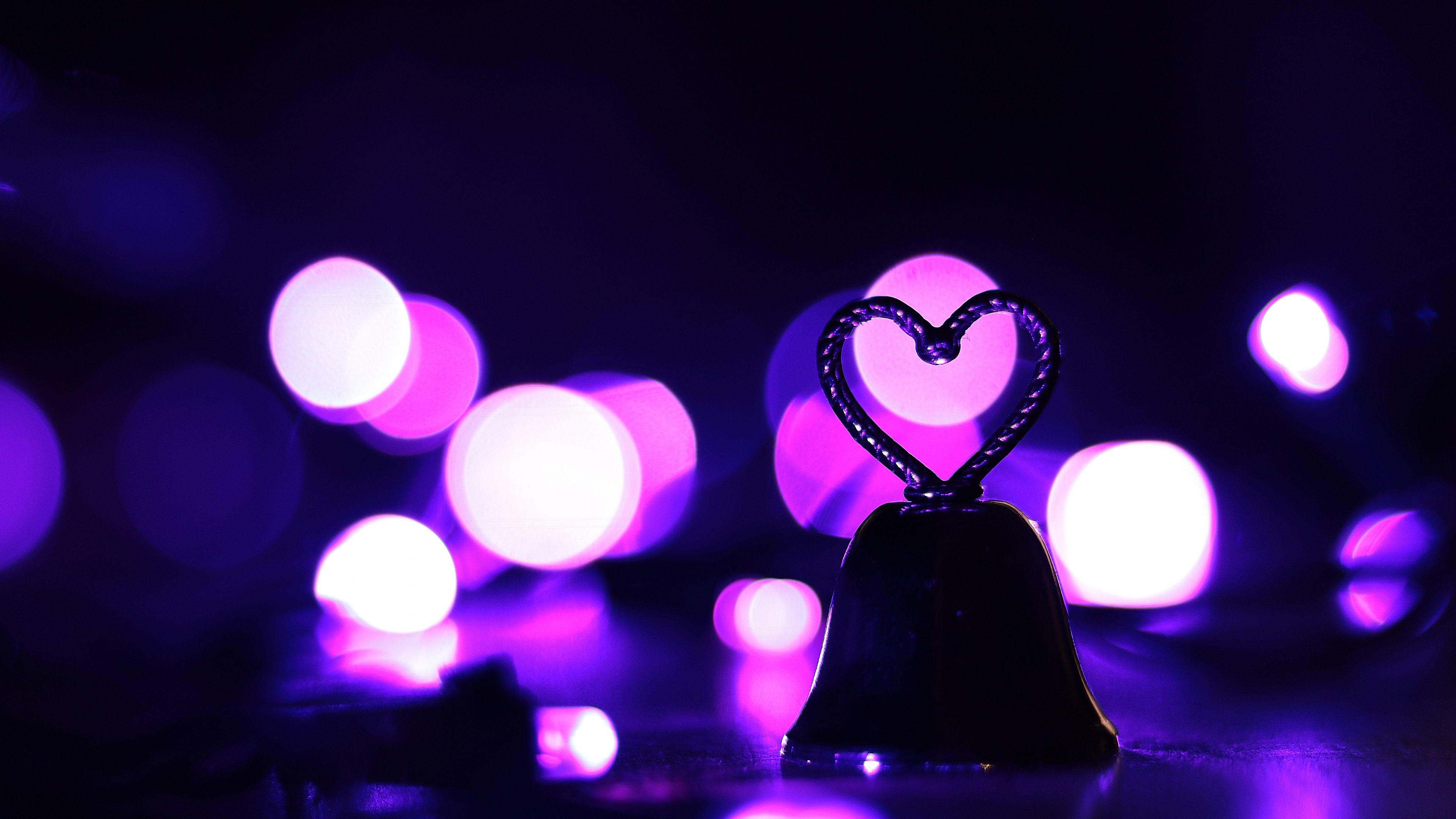 A heart shaped bell in front of purple bokeh lights. - Cute purple