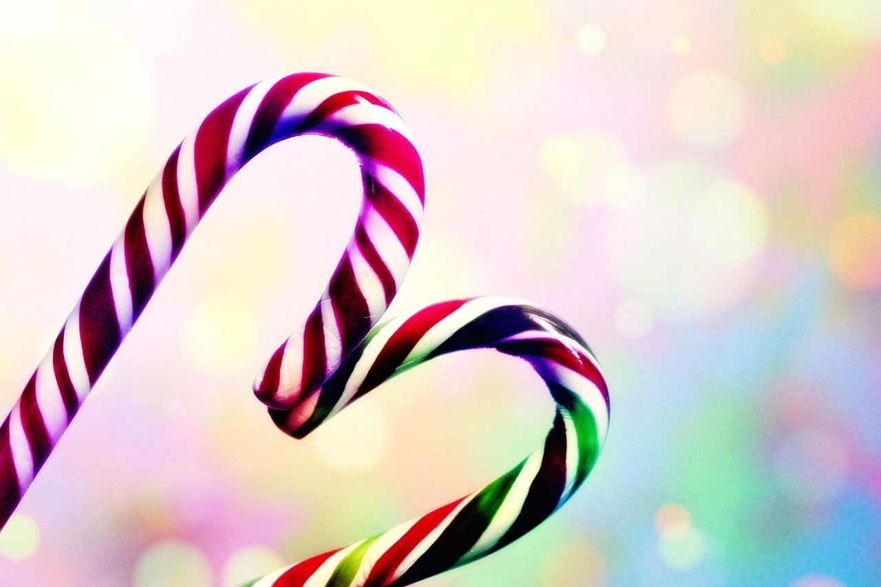 A pair of candy canes in front of a colorful background - Candy cane