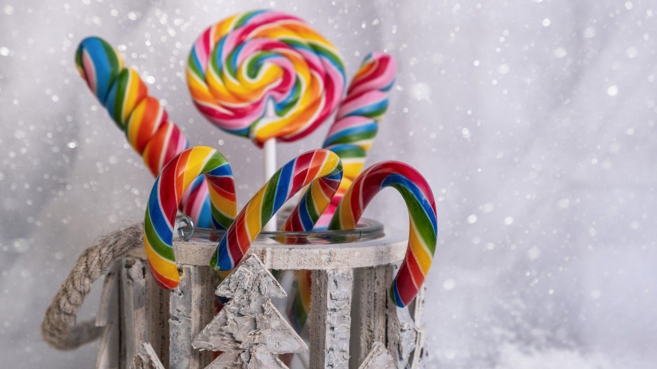 A jar of colorful lollipops on a snowy background. - Candy cane