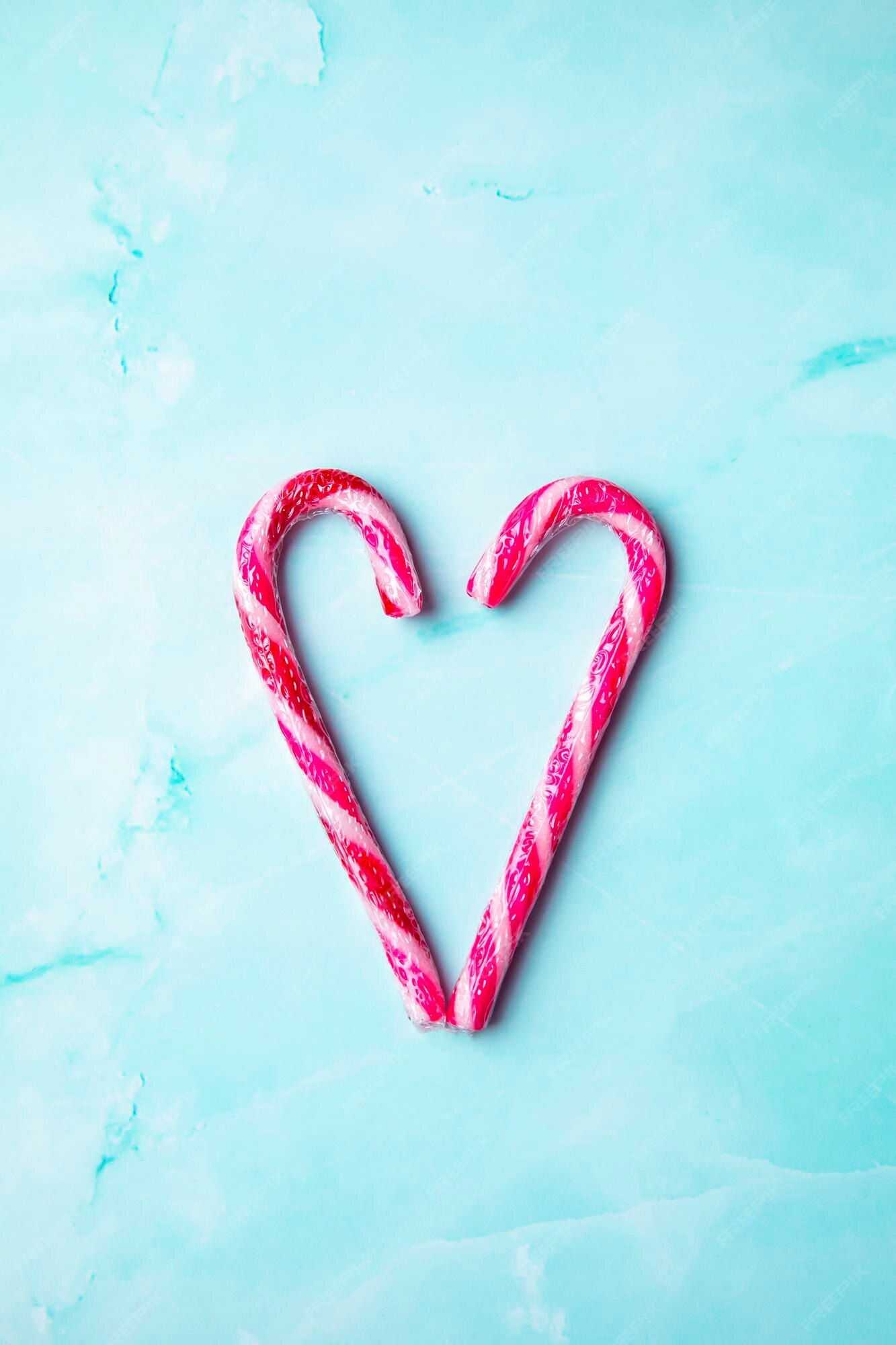 Two candy canes forming a heart shape on a blue background - Candy cane