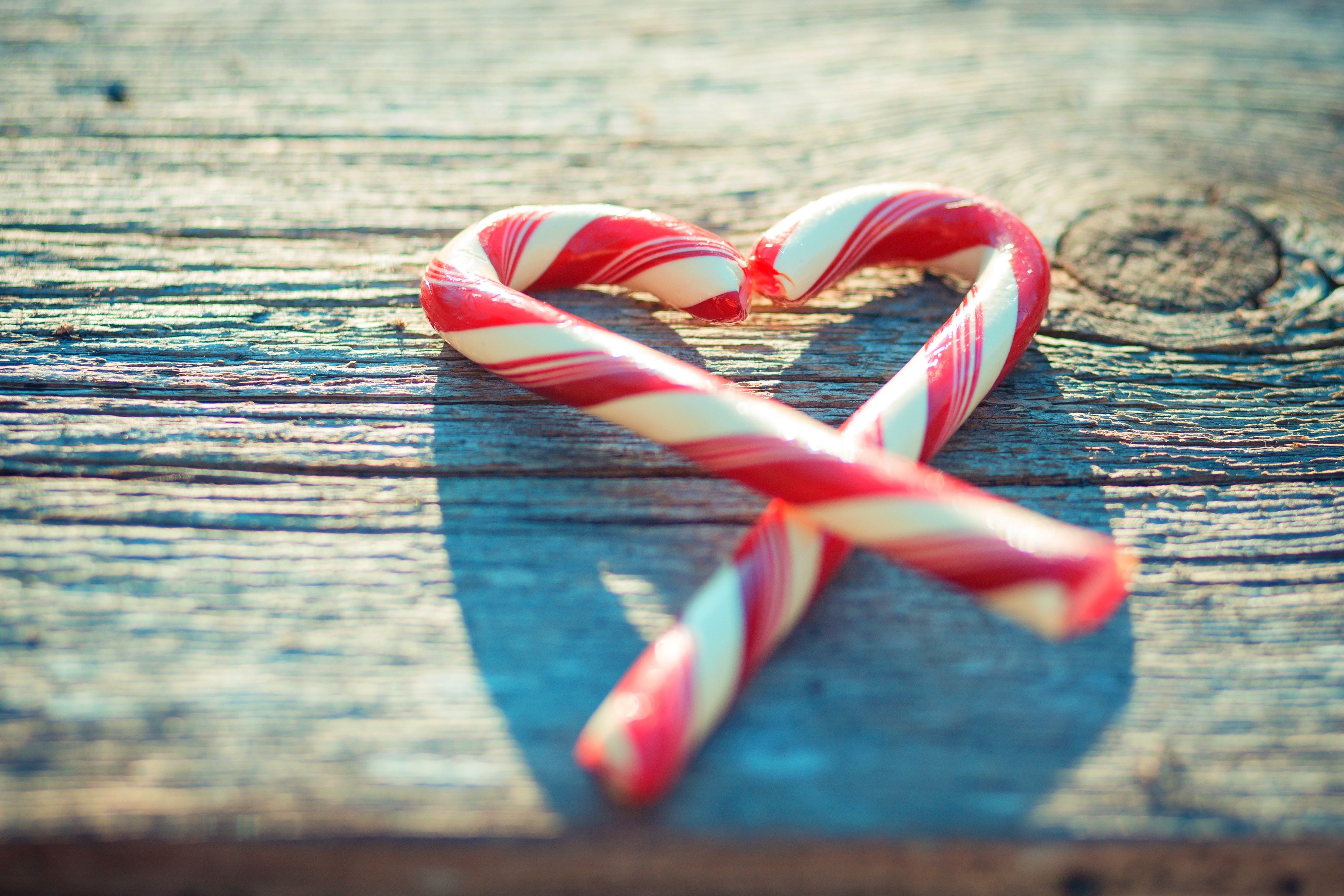 Two candy canes in the shape of a heart on a wooden table - Candy cane