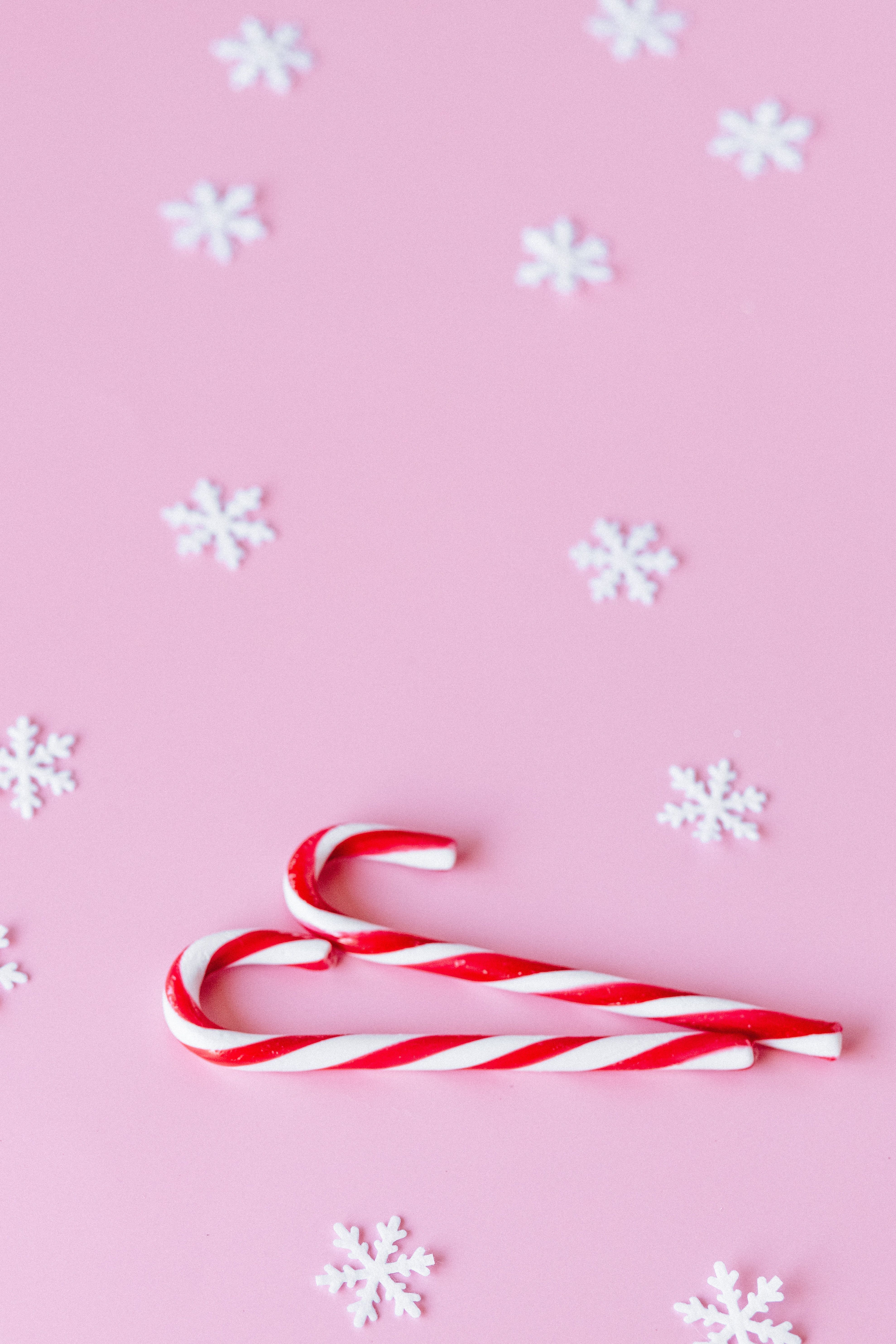 A pink background with candy canes and snowflakes. - Candy cane