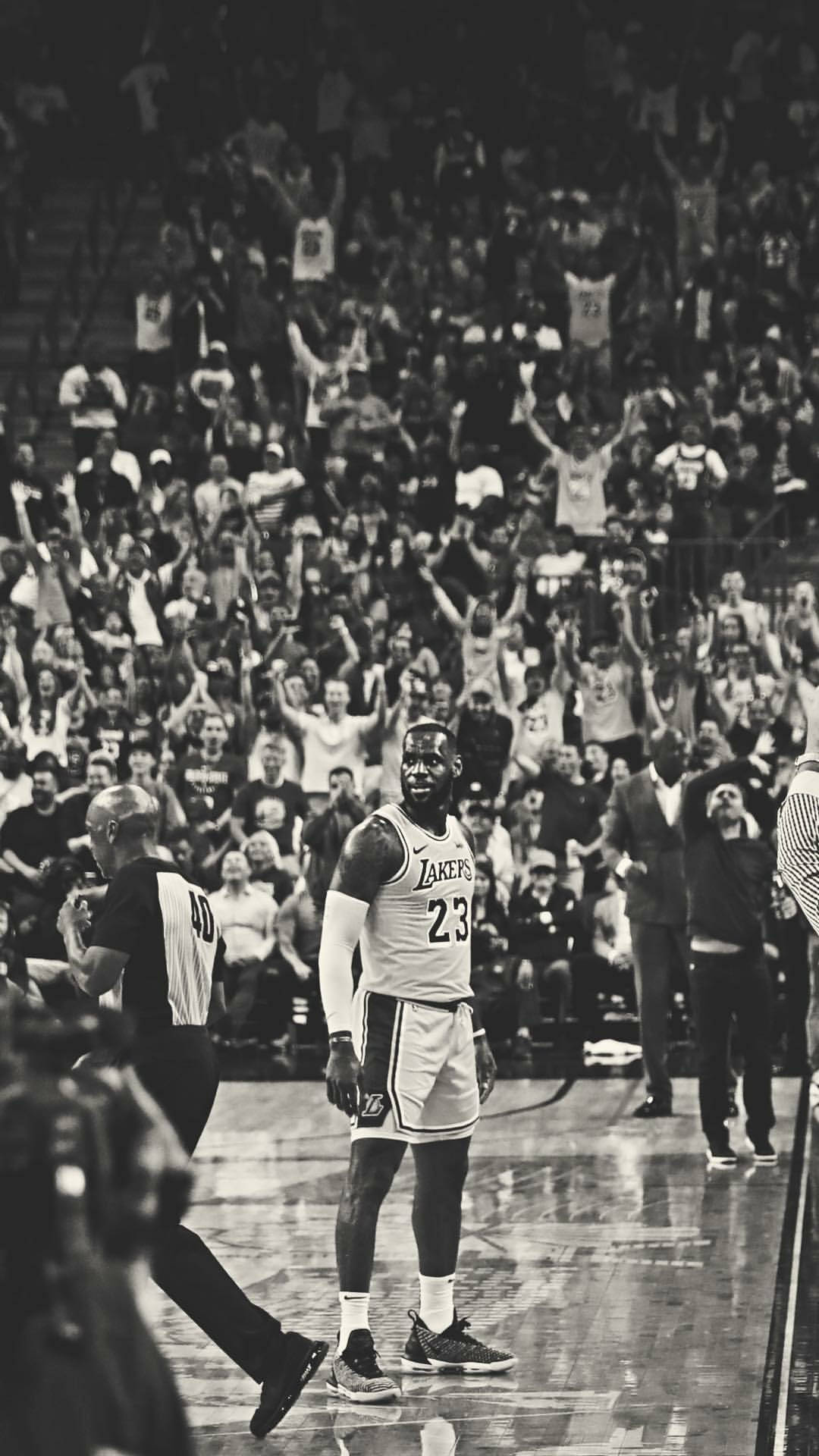 A black and white photo of a basketball player on the court with a crowd of fans behind him. - Lebron James