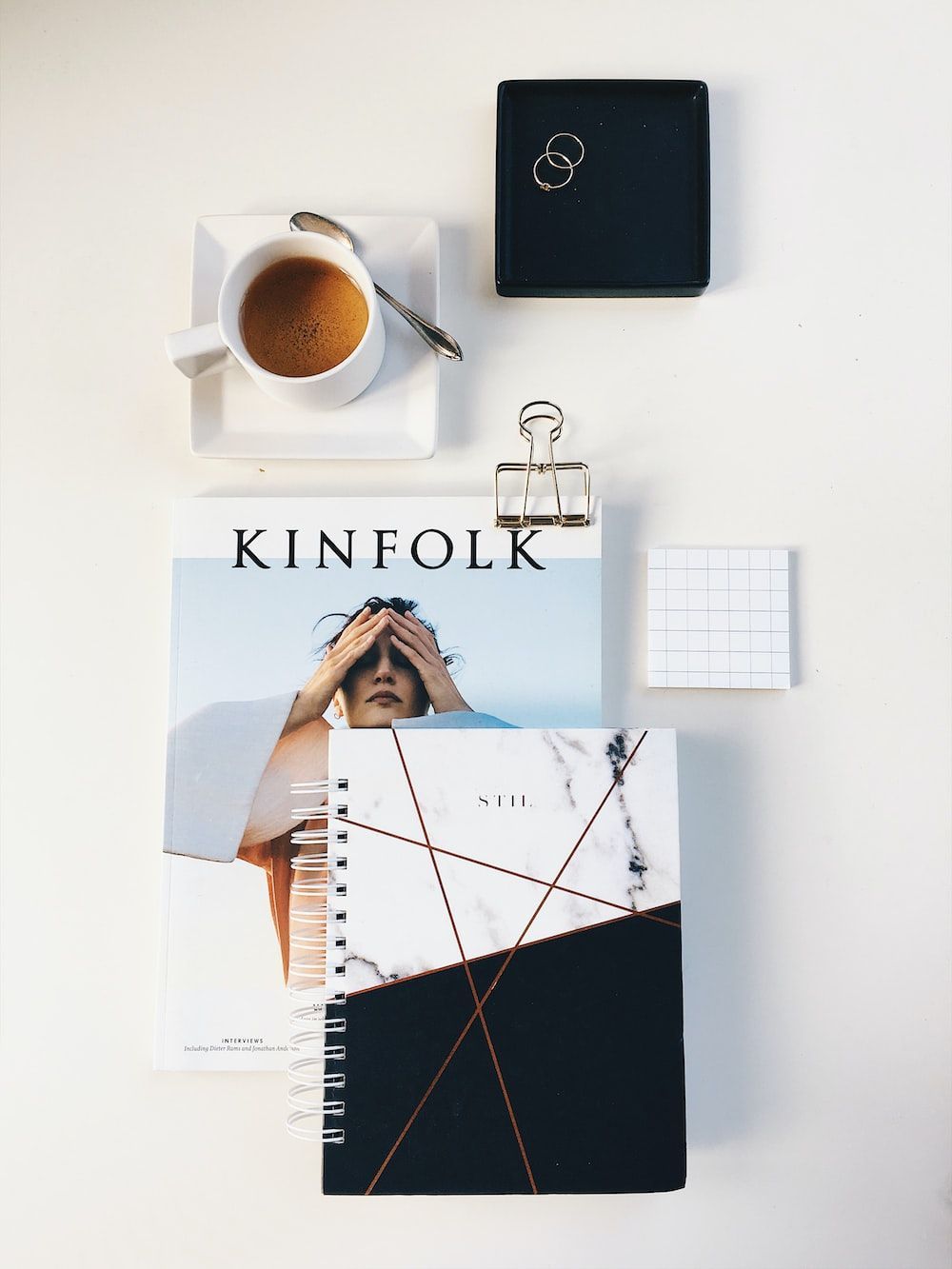 Flat lay photography of cup, rings, and notebook photo