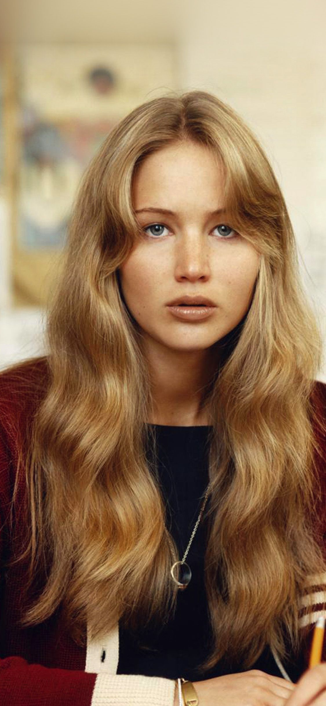 Jennifer Lawrence with long blonde hair and bangs, wearing a black shirt and a red cardigan. - Jennifer Lawrence