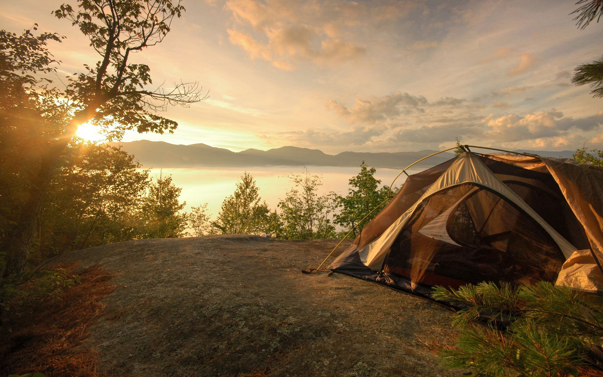 A tent on a cliff overlooking a lake at sunset - Camping