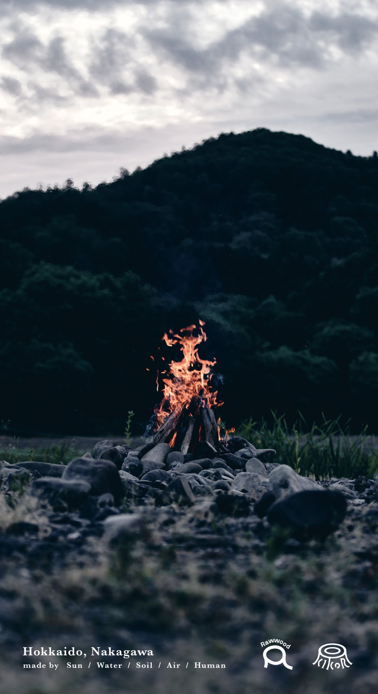 A small campfire burns in the middle of a rocky field. - Camping