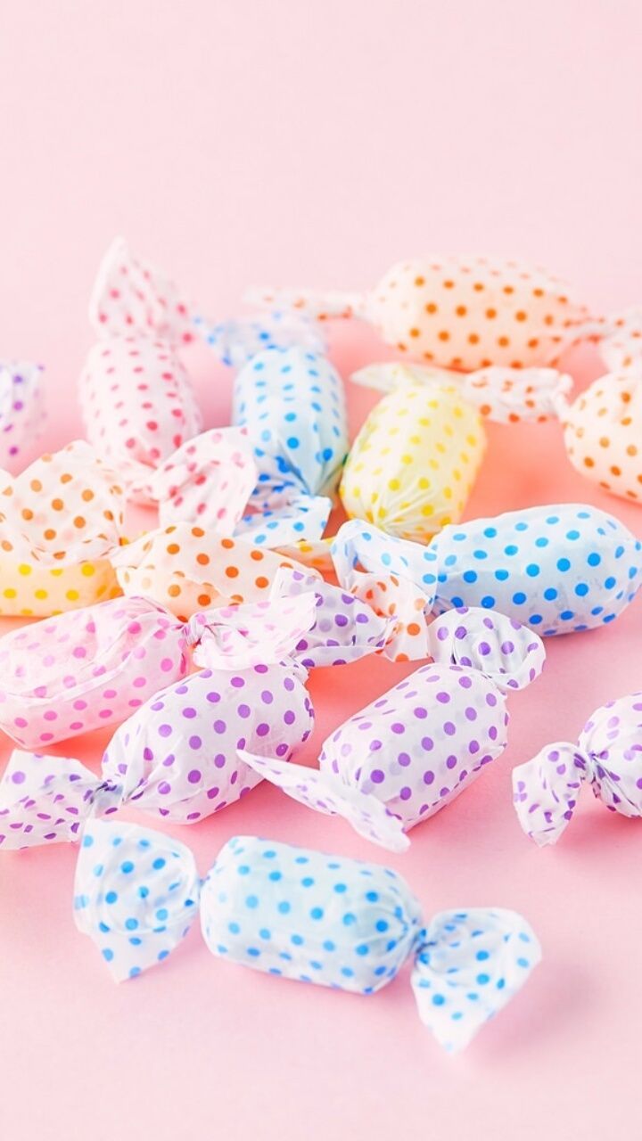 Polka dot wrapped candies on a pink background - Candy