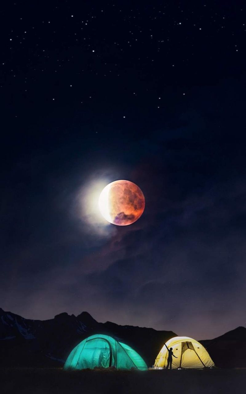 The moon is red and there are three tents in the foreground. - Camping