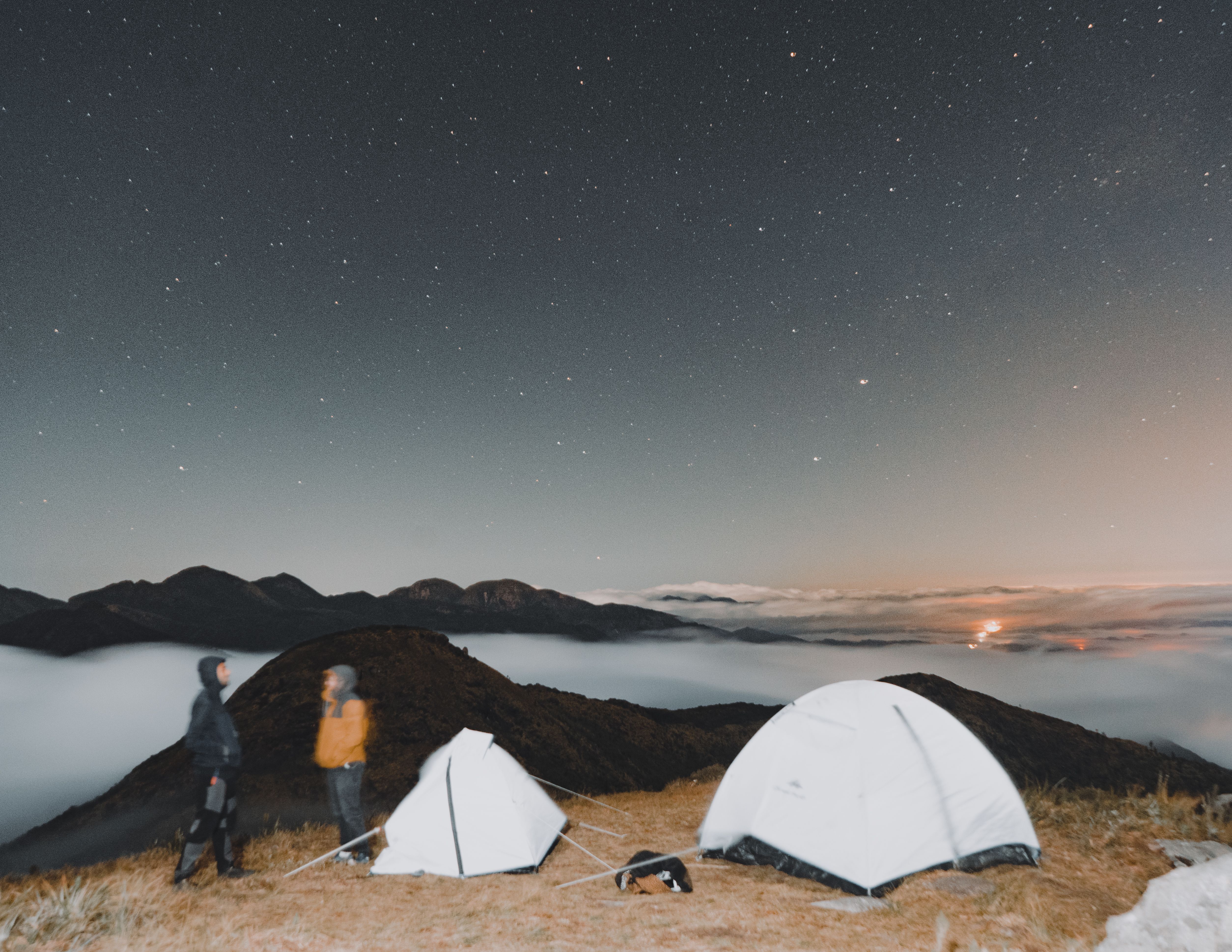 Two people standing outside their tents under a starry sky - Camping