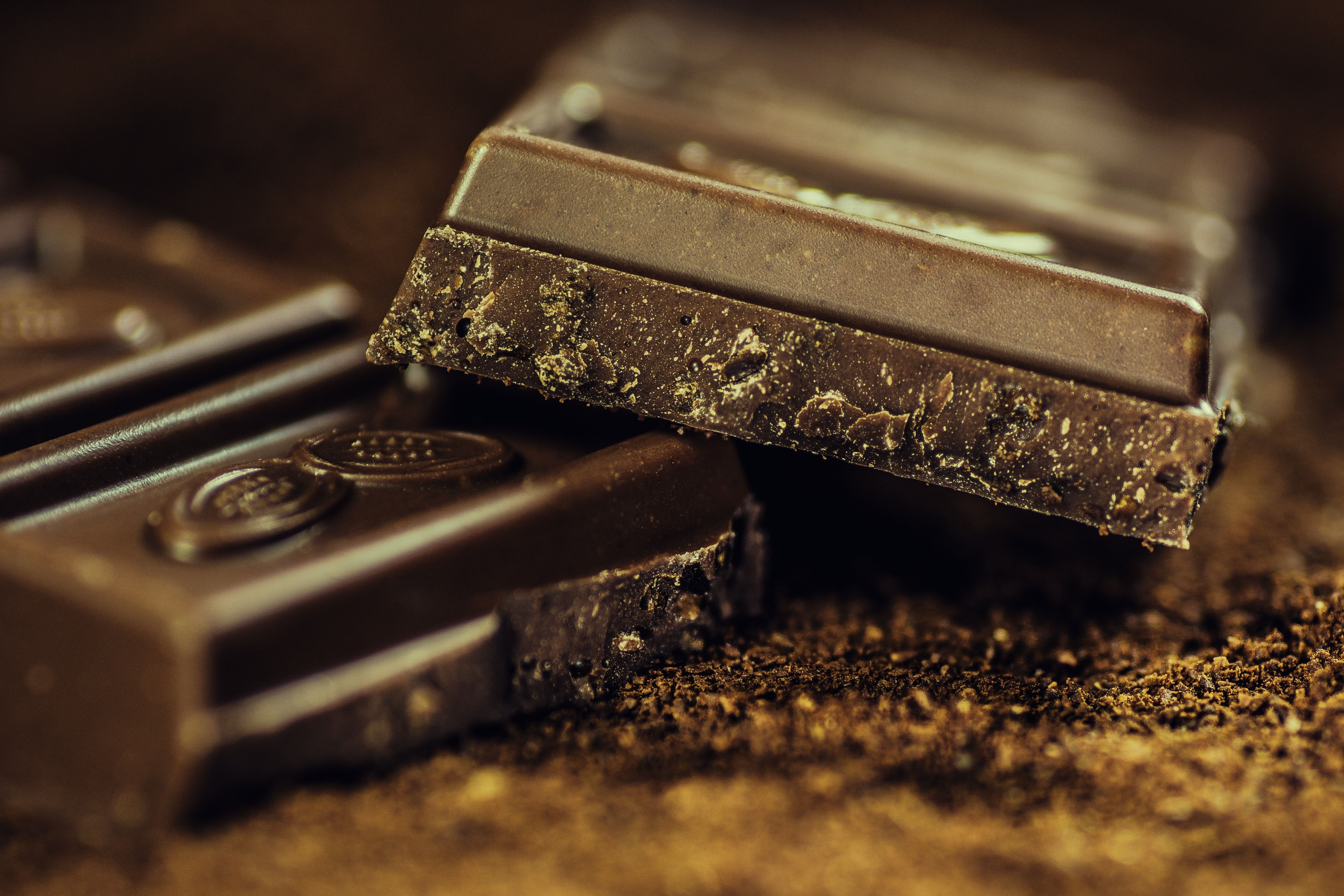 A close up of a pile of chocolate bars on a wooden table. - Chocolate