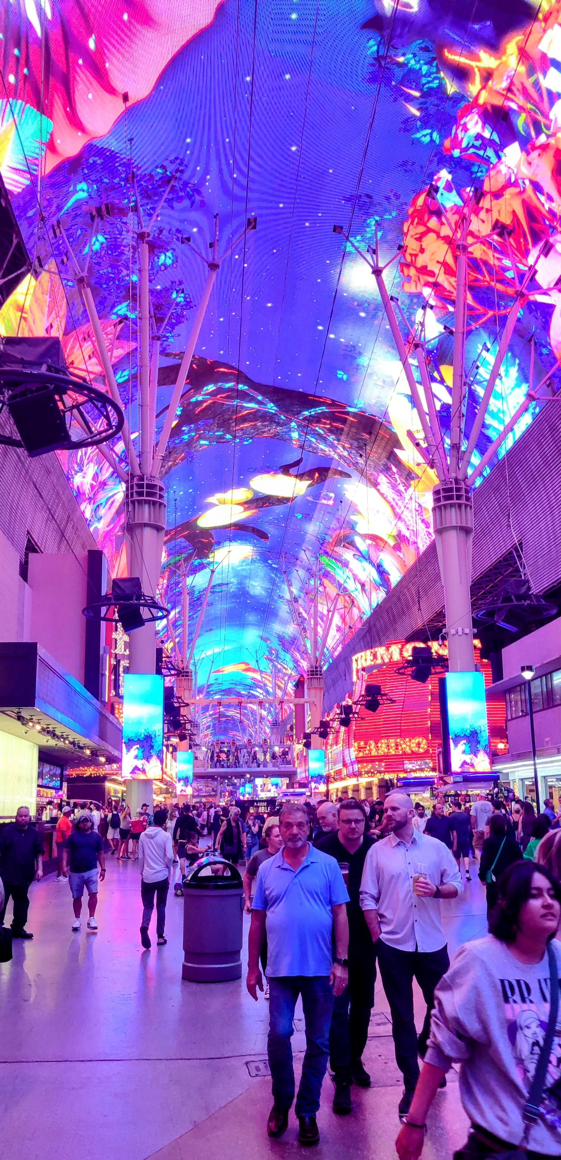 People walking through a colorful neon-lit shopping center. - Las Vegas