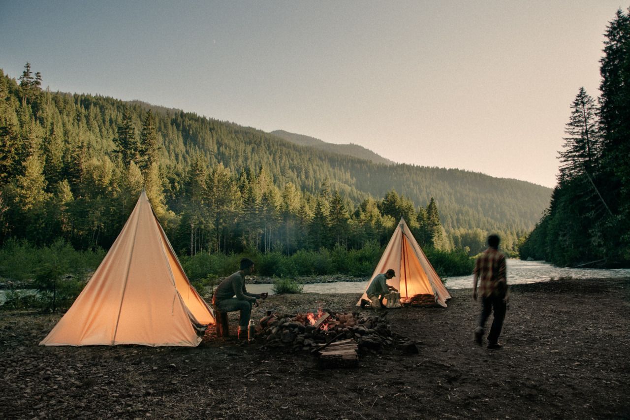 A group of people standing next to some tents - Camping