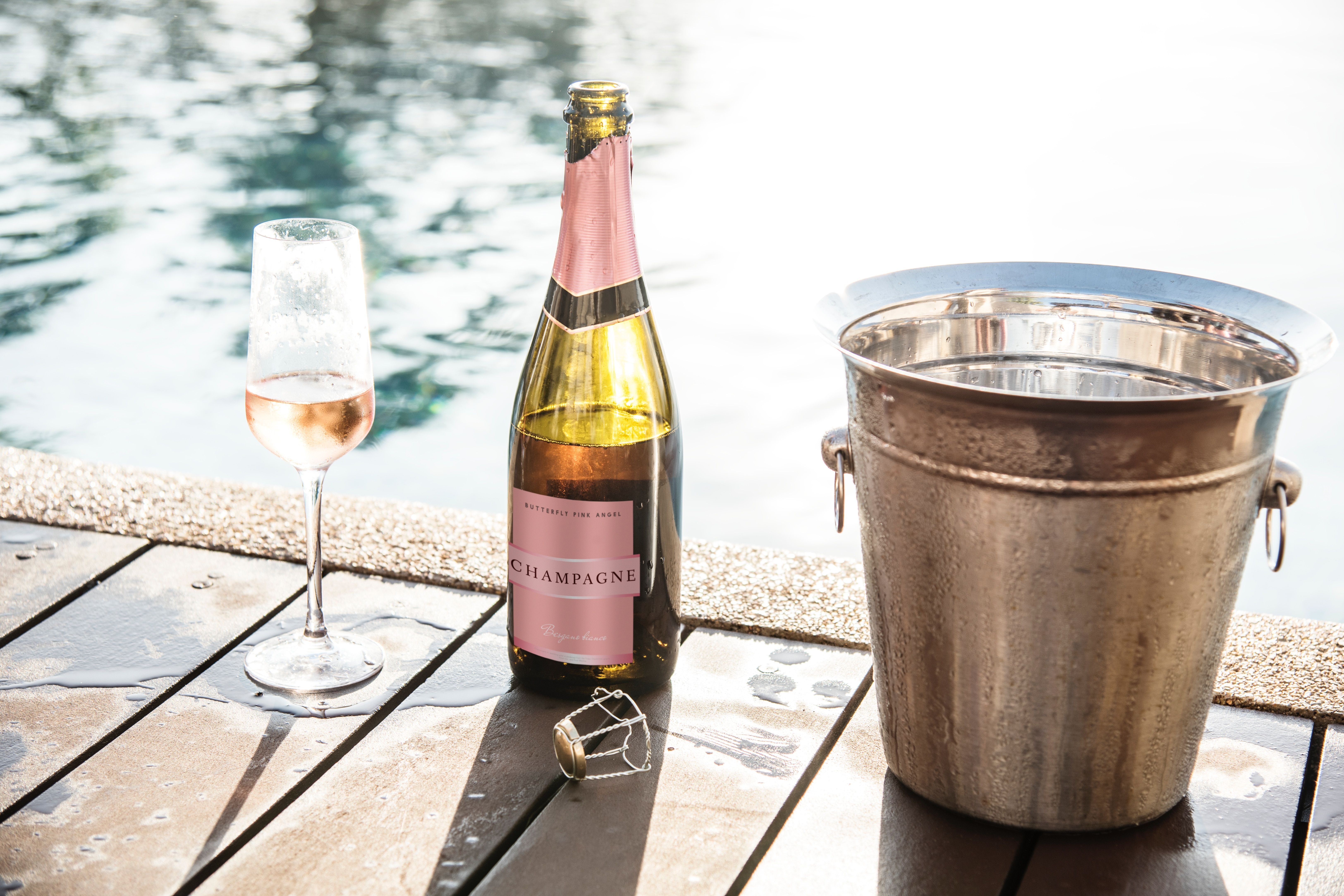 A bottle of champagne sits next to a bucket of ice and a glass of champagne. - Champagne