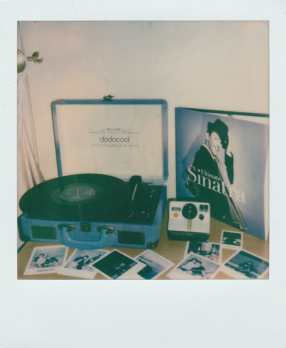 A record player and Polaroid camera sit on a table. - Polaroid