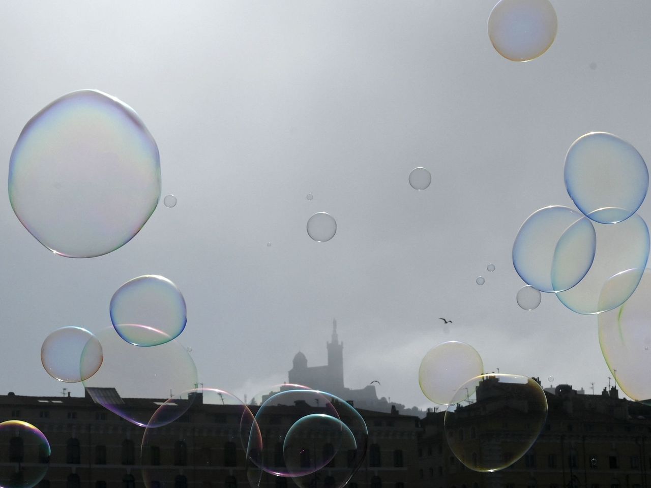 Bubbles floating in the air with a building in the background - Bubbles