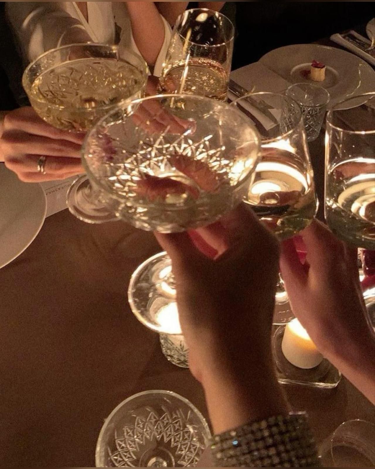 People holding up glasses of champagne at a table. - Champagne