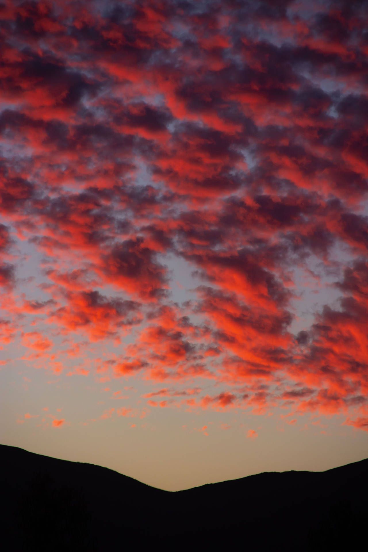 A sunset with clouds and mountains in the background - Crimson