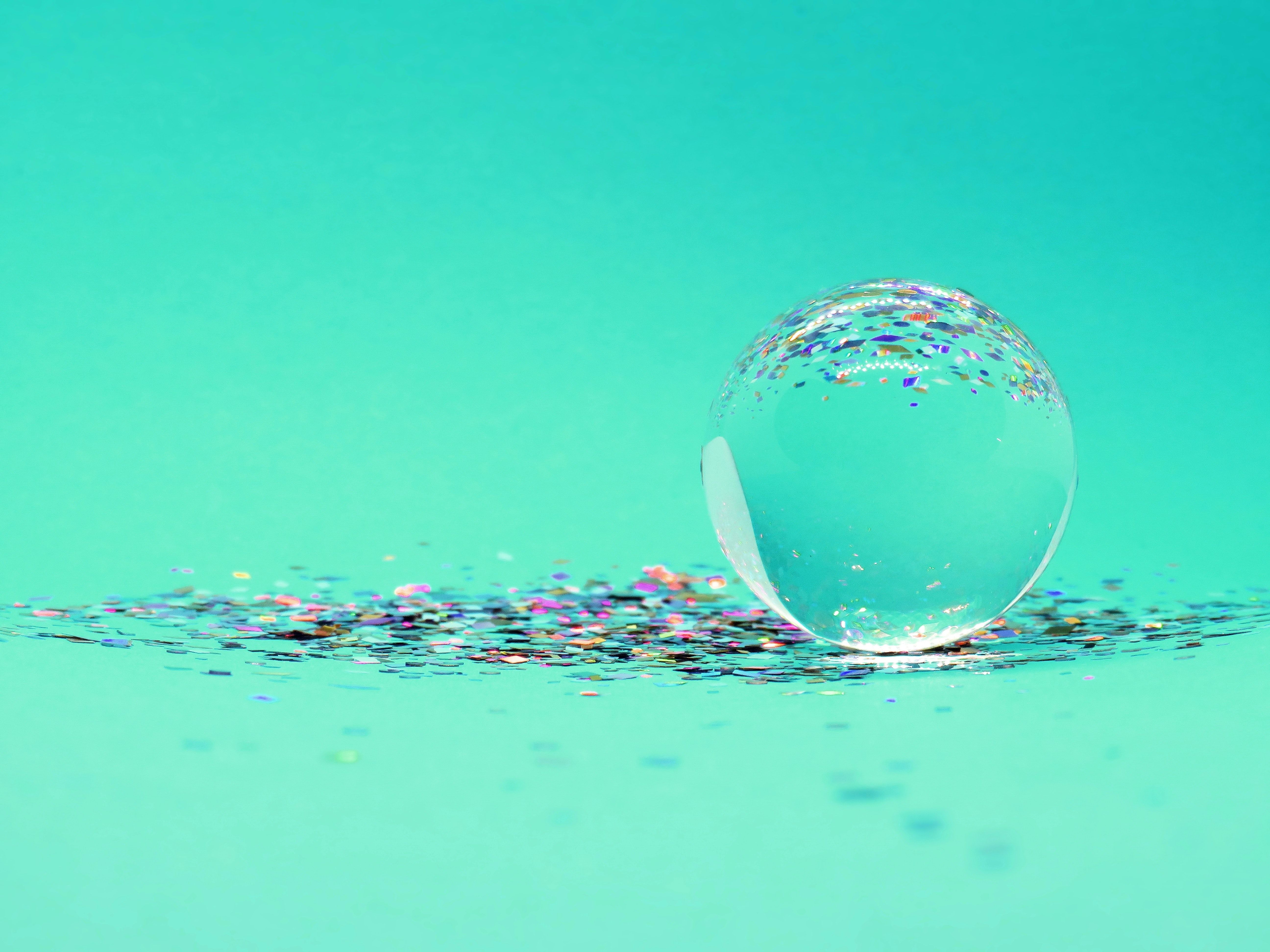 A glass sphere on a blue background with confetti - Bubbles