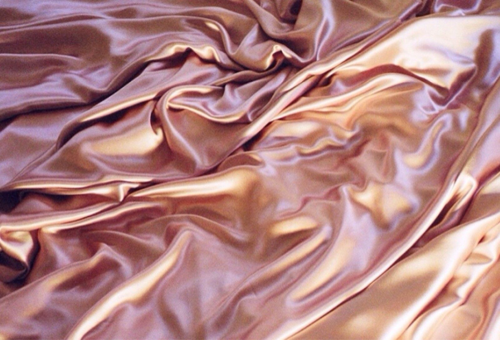 A bed with a pink silk sheet on it - Rose gold, silk