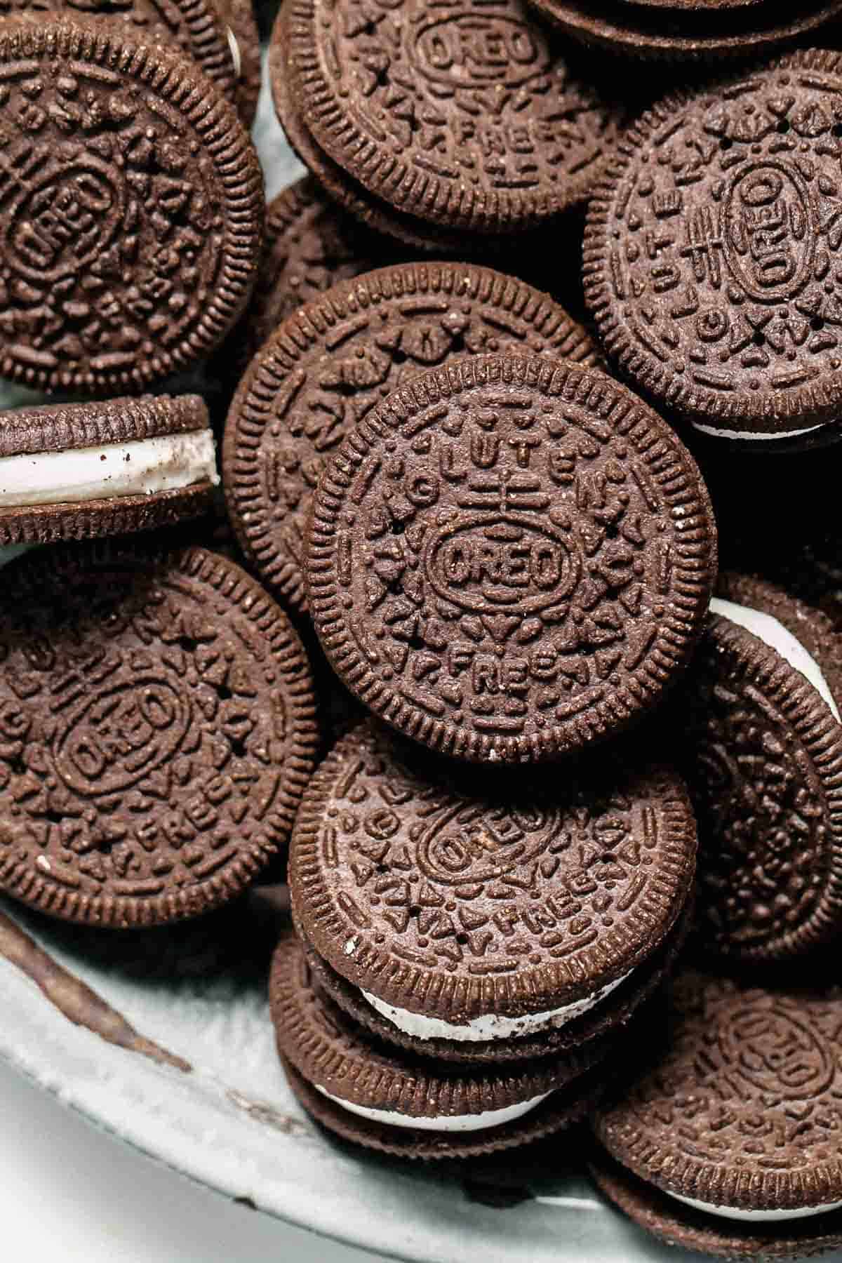 A plate of chocolate sandwich cookies with white filling. - Oreo