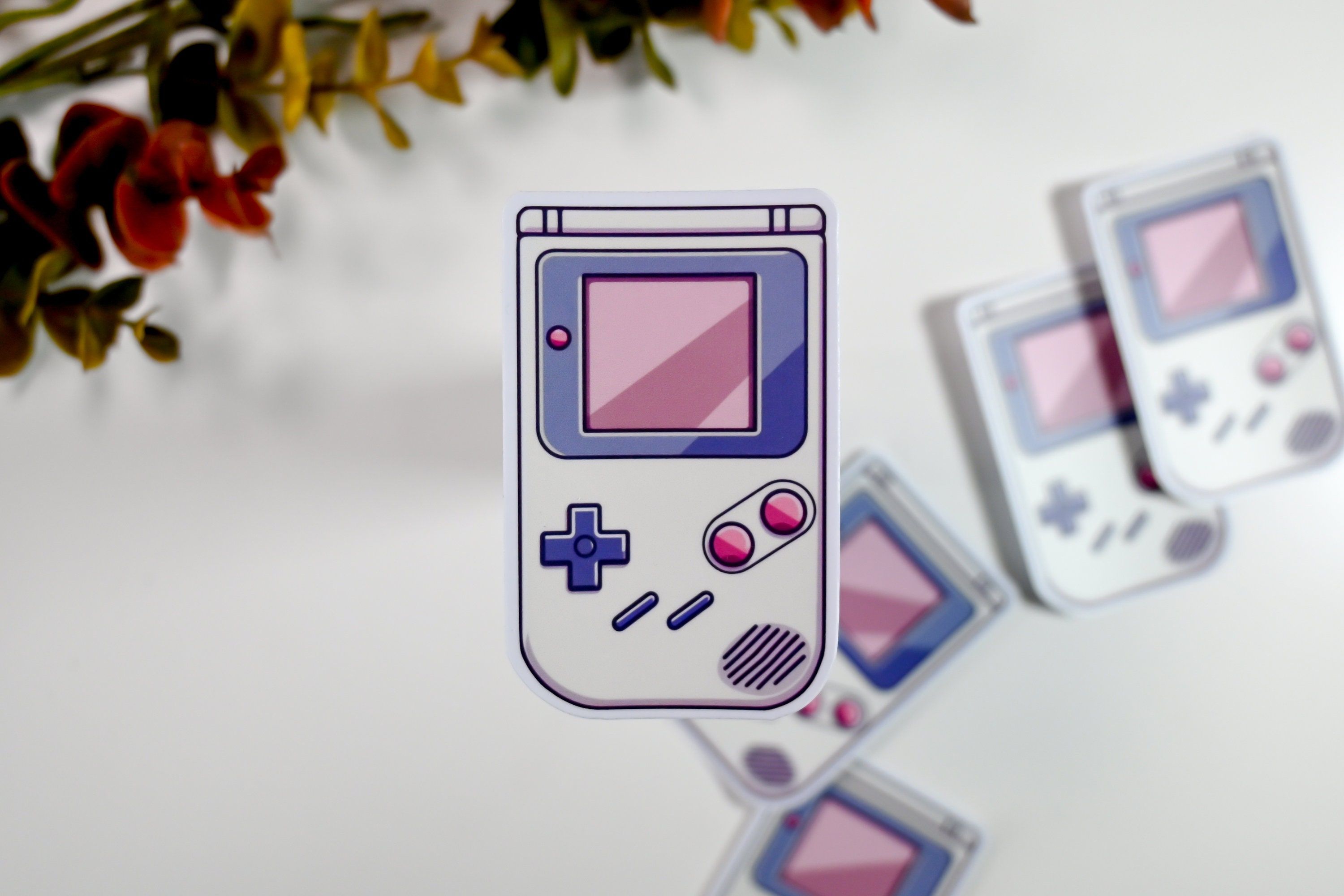 A sticker of a Gameboy console in purple and blue. - Game Boy