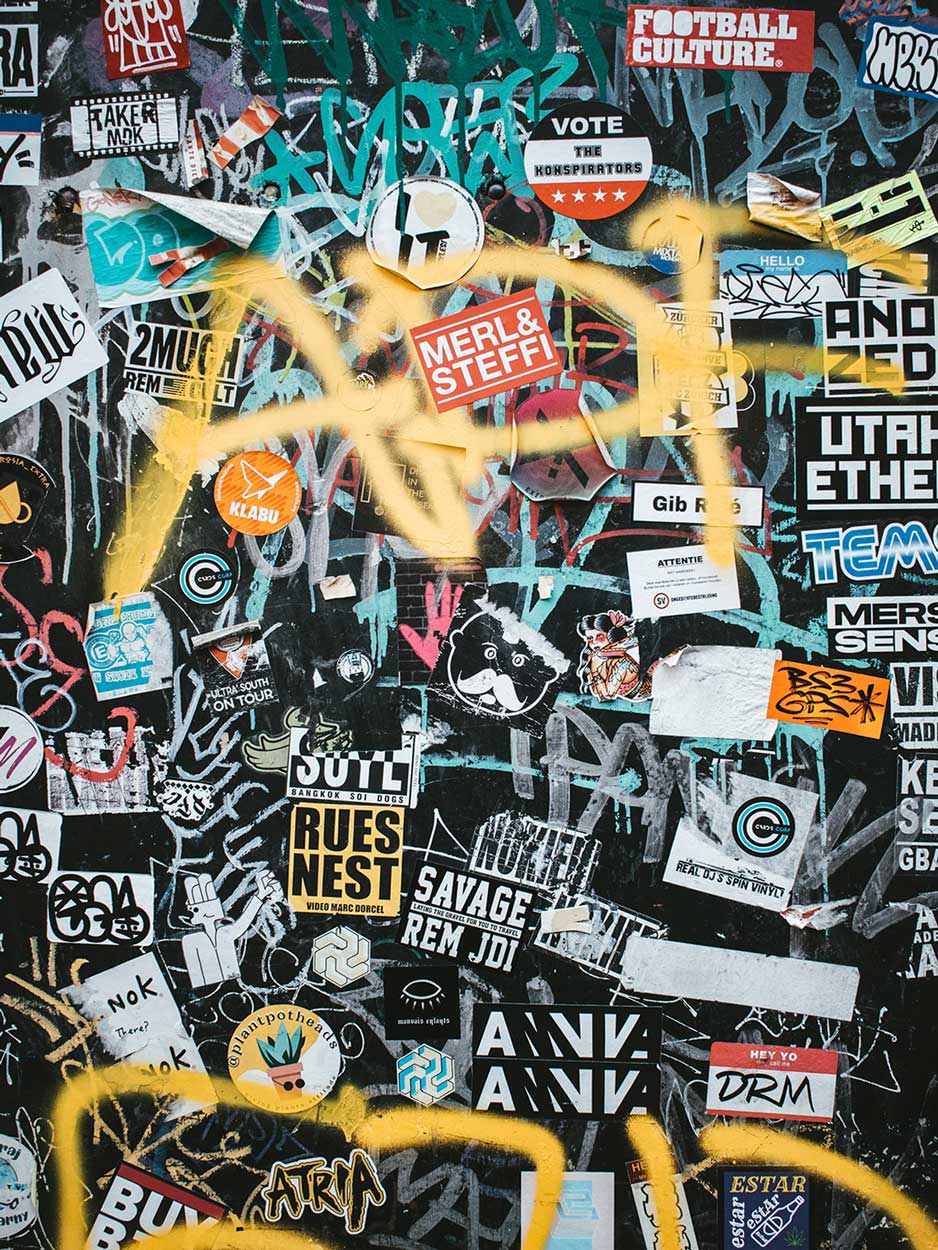A wall covered in stickers and graffiti - Graffiti
