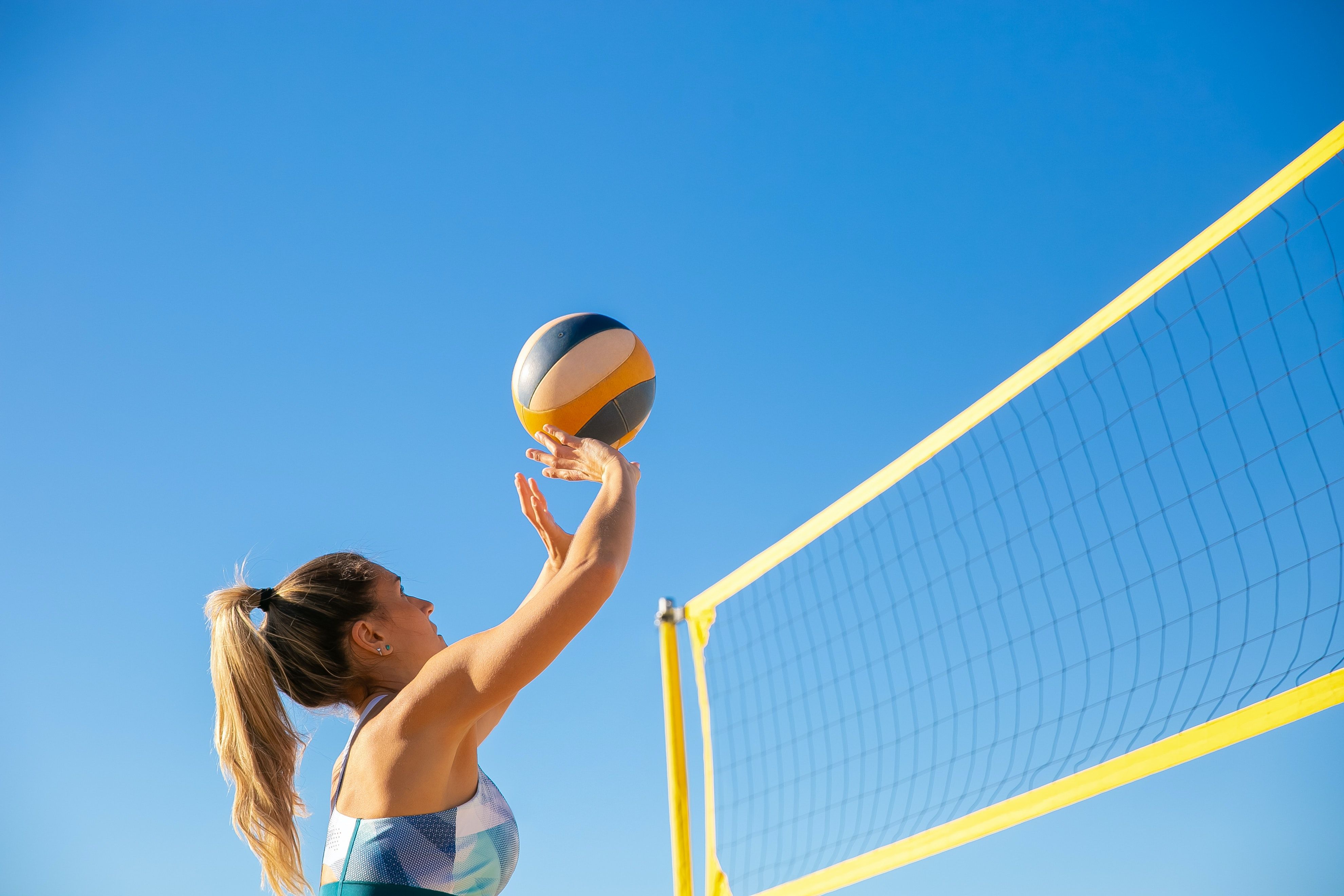 A woman hitting a volleyball over the net - Volleyball