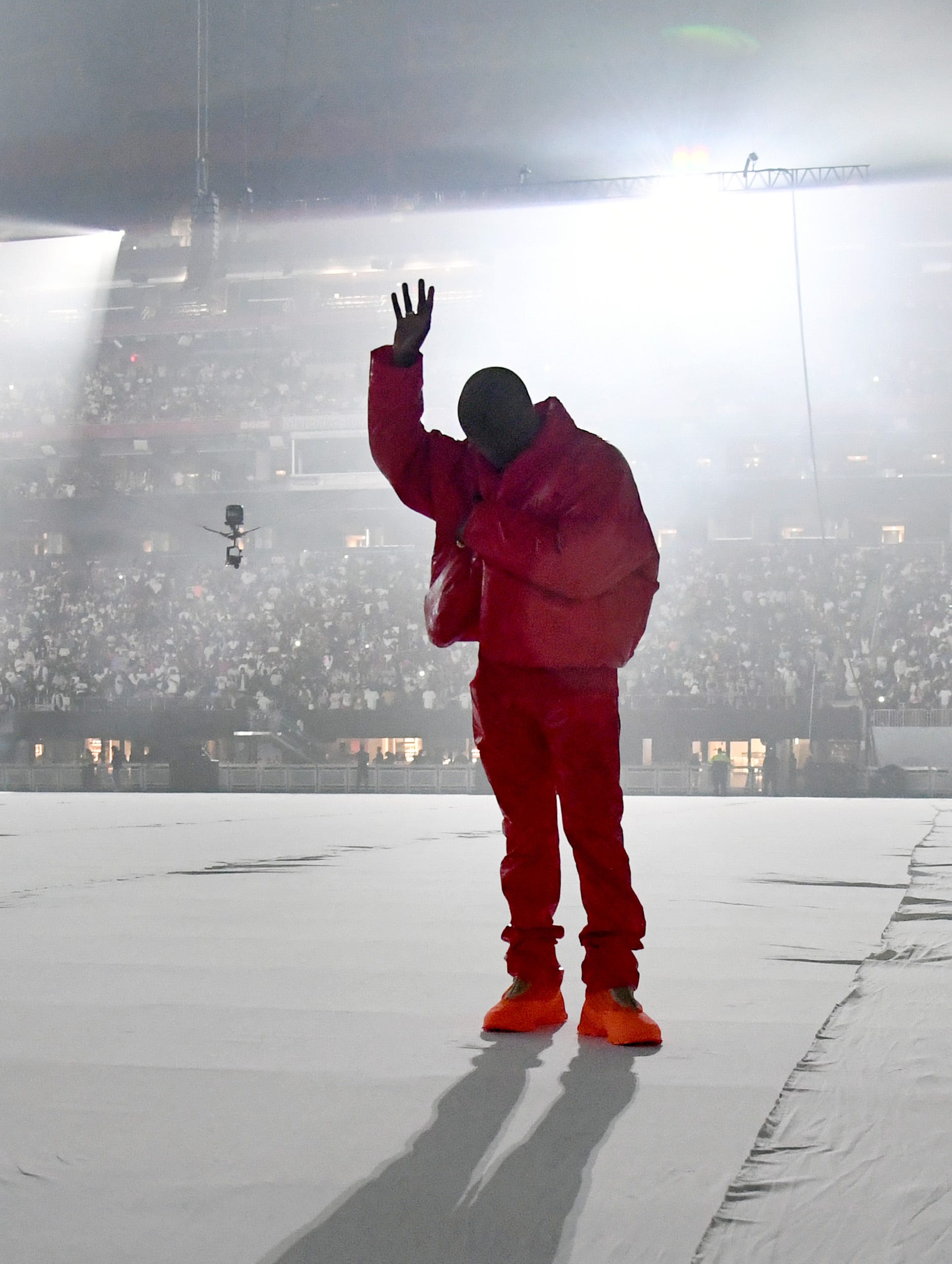 Kanye West wearing a red outfit on stage - Kanye West