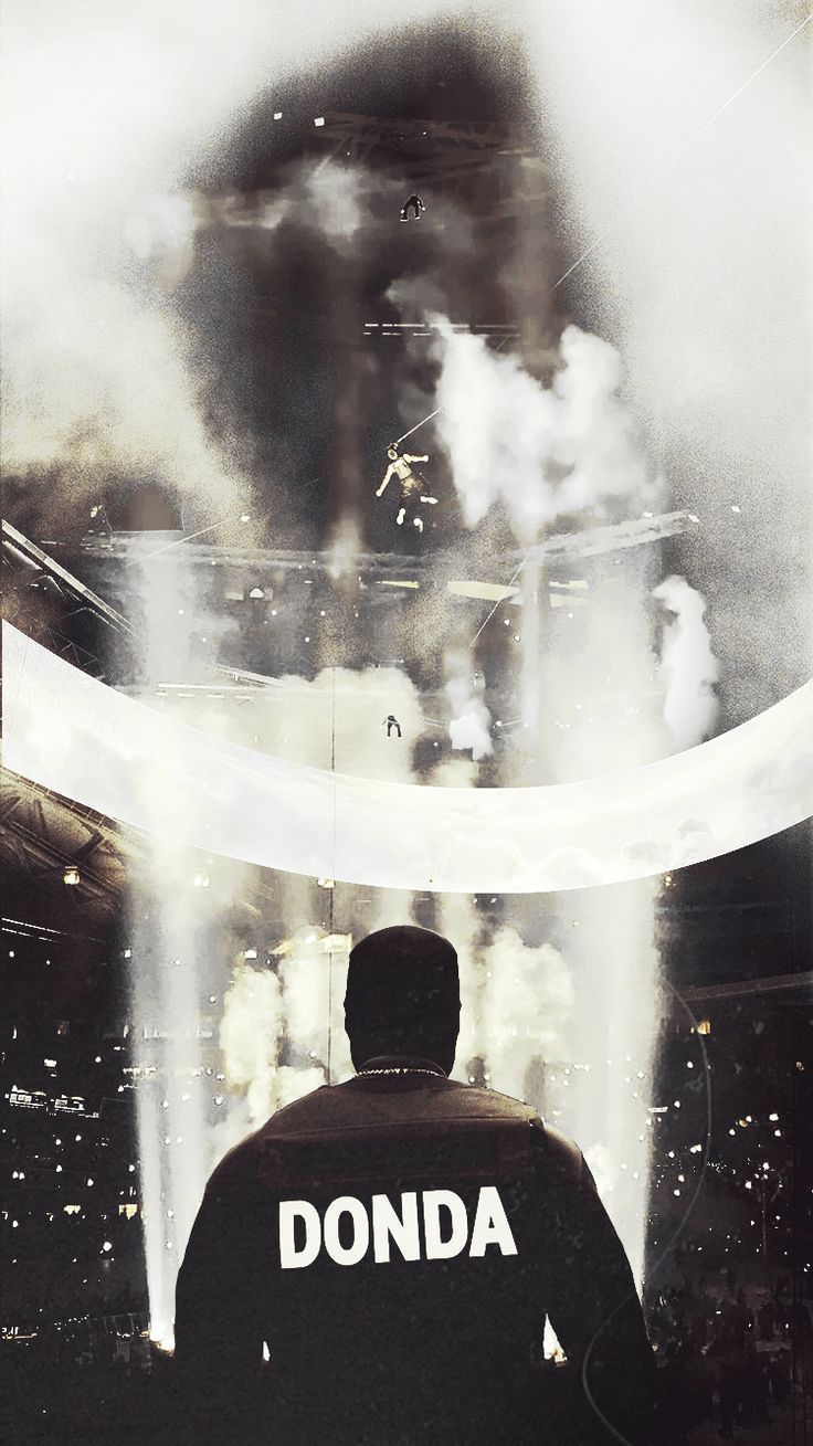 A man wearing a shirt that says Donda in front of a stage with smoke - Kanye West