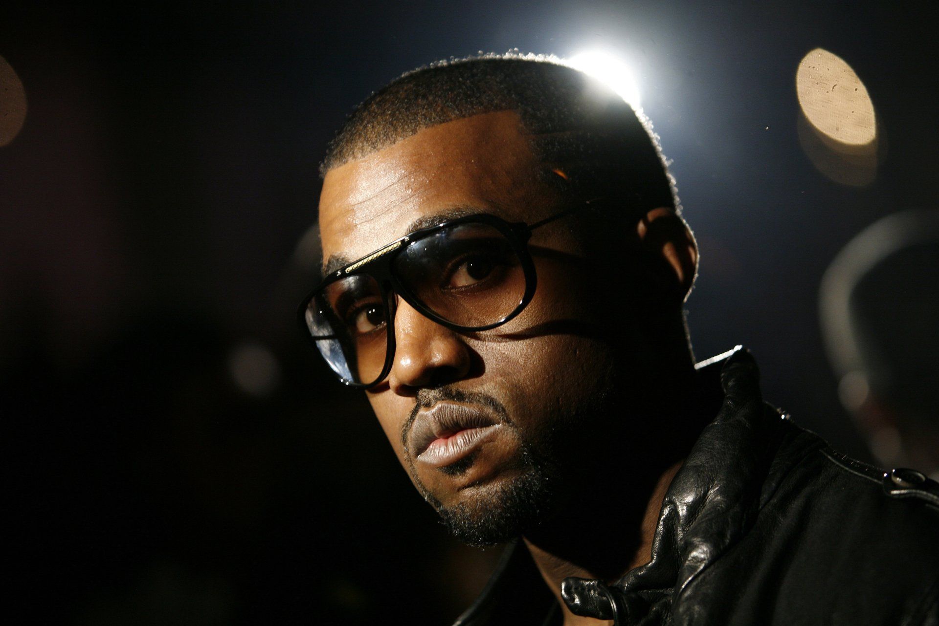 Kanye West is wearing glasses and looking to the side. - Kanye West