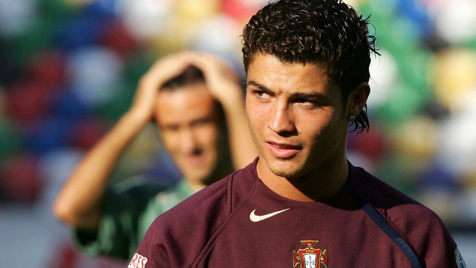 Young Cristiano Ronaldo Is Wearing Dark Maroon Sports Dress Standing In Colorful Blur Background HD Ronaldo Wallpaper