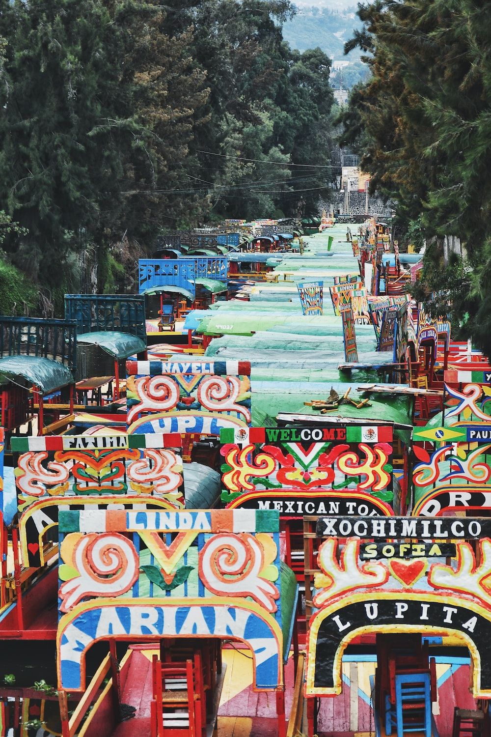 A colorful boat filled street with trees in the background. - Mexico